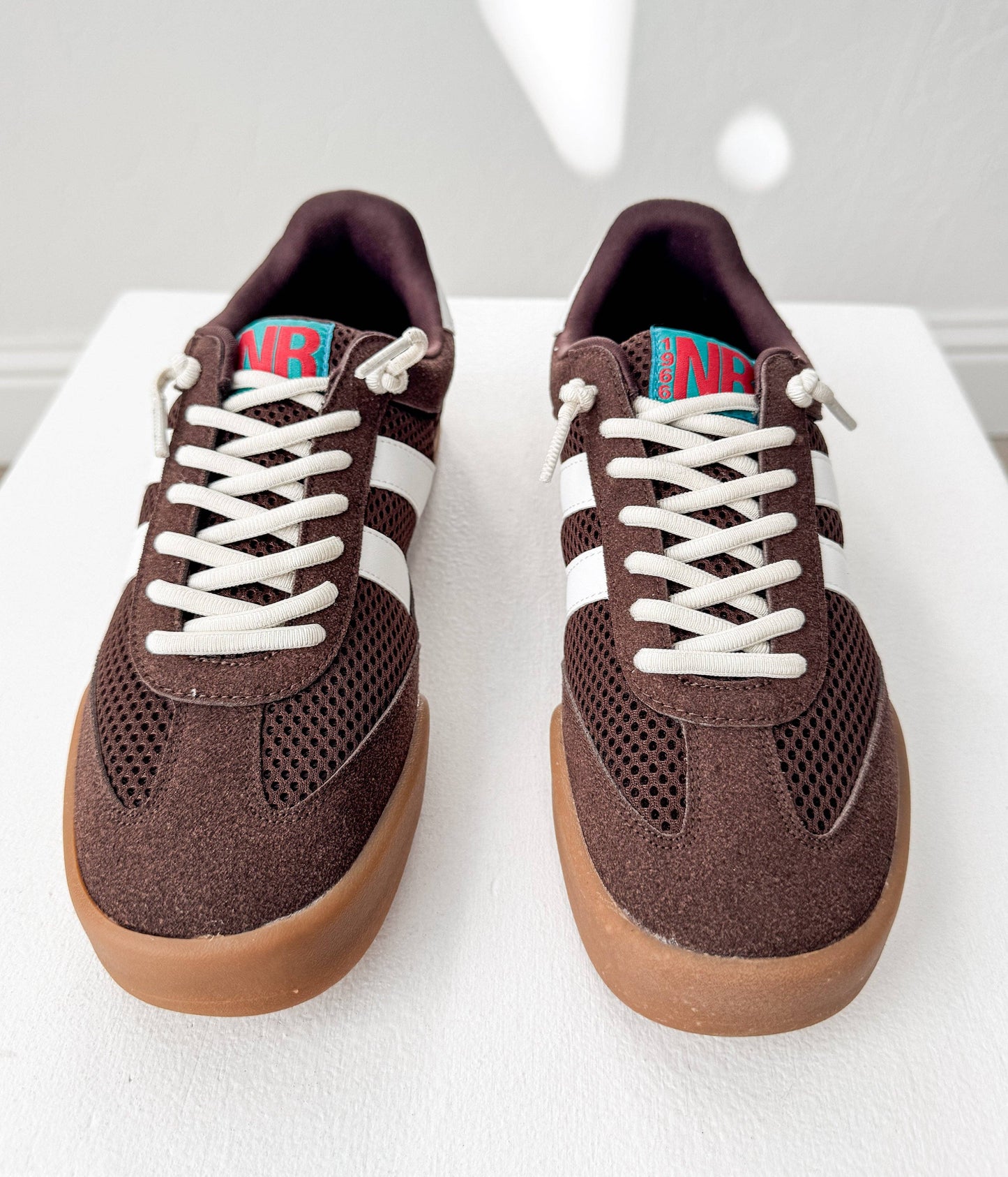 Side angle of mocha brown vintage-inspired sneakers with white stripes and gum soles on a white background.