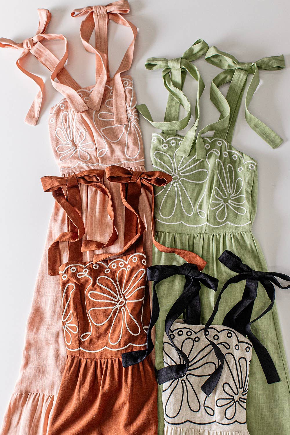 Four dresses in different colors with floral patterns on a white background