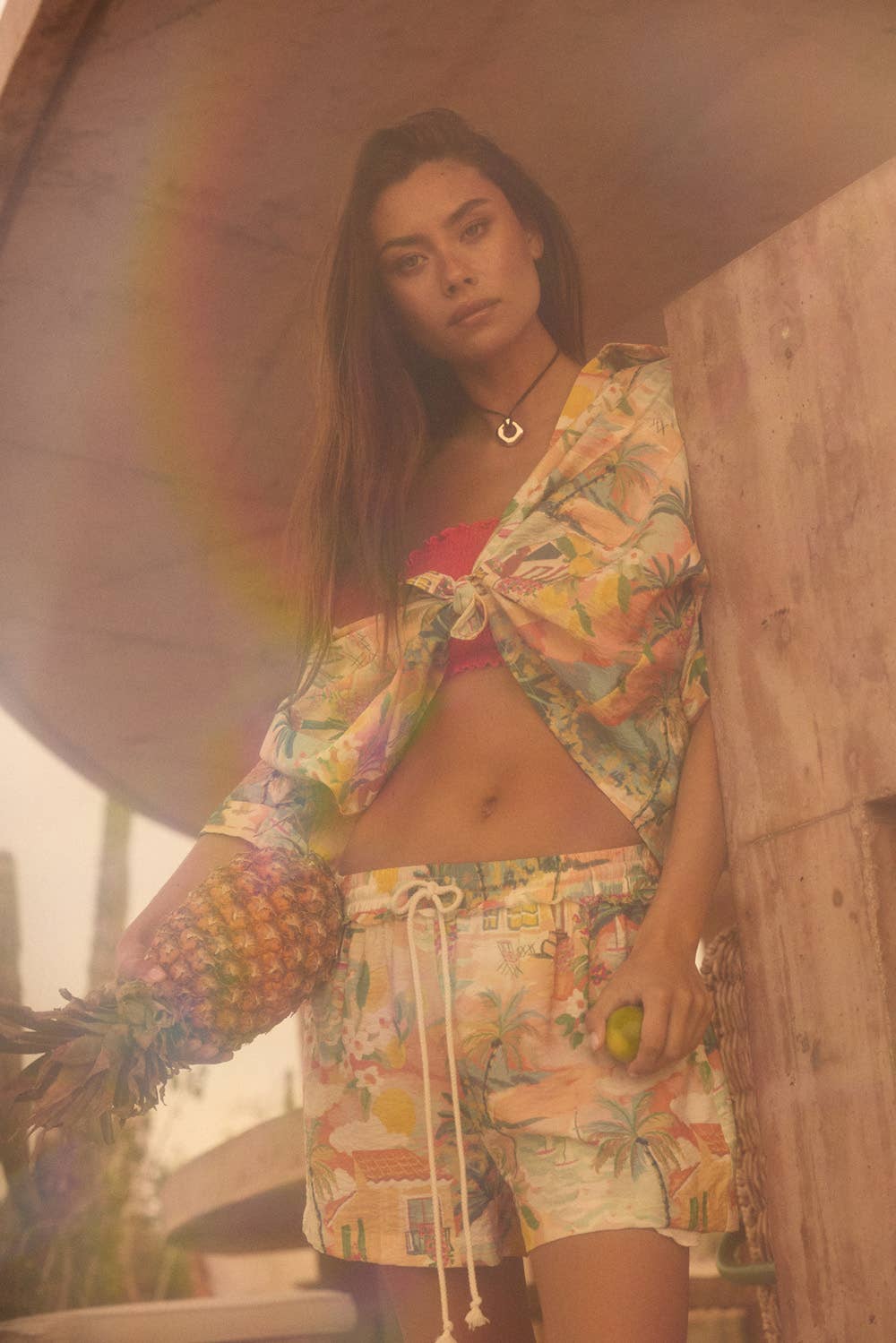 Woman in a colorful tropical print outfit standing under a rainbow