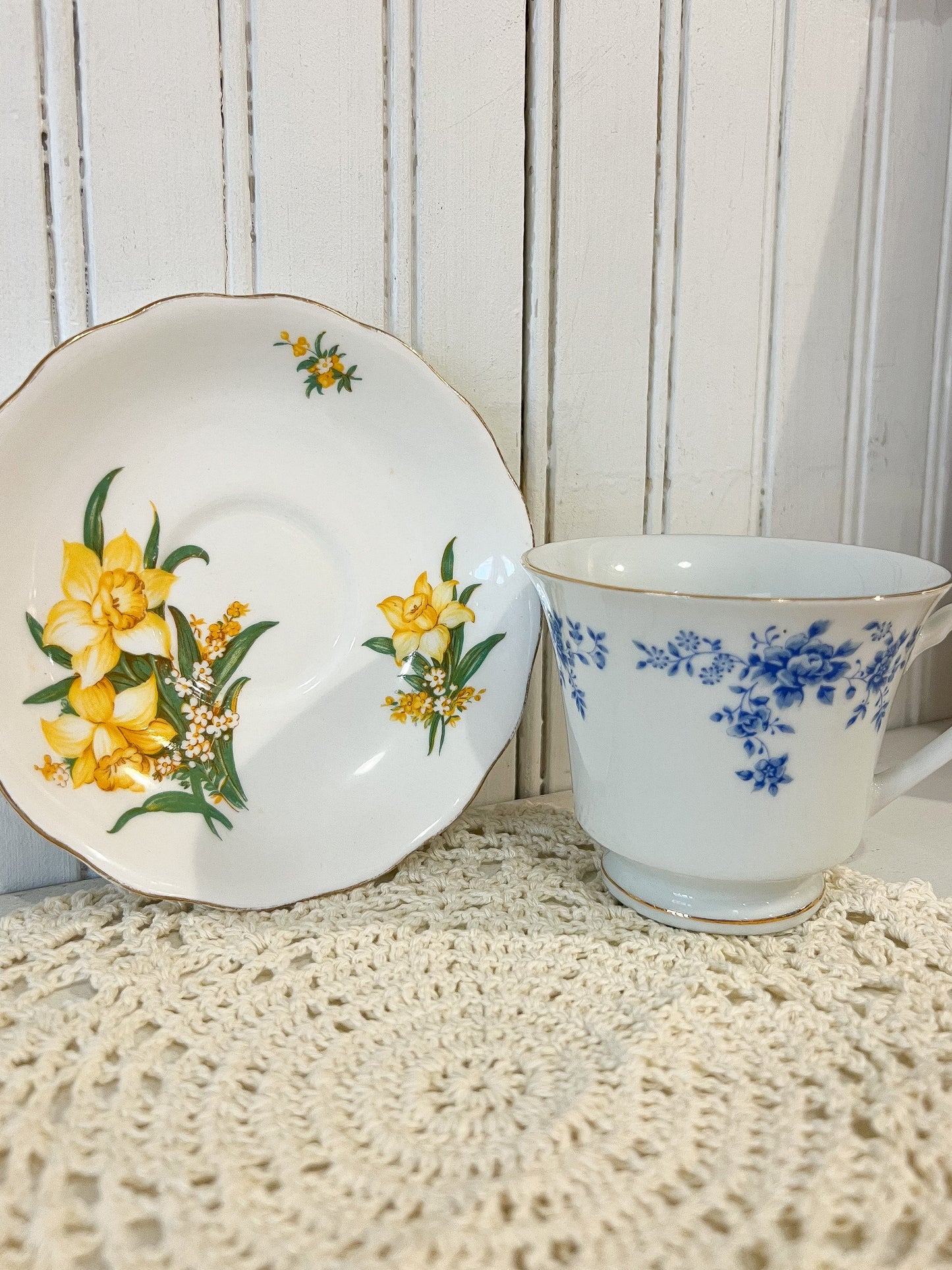 Vintage ceramic cup and saucer with floral designs on a textured surface.