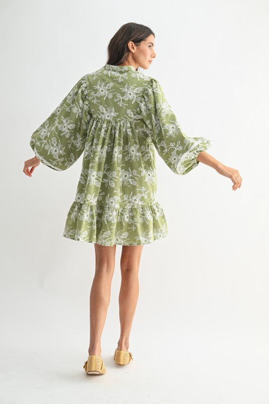 Back view of green gingham embroidered mini dress with tiered ruffle hem and oversized sleeves — flowy cottagecore boho outfit.