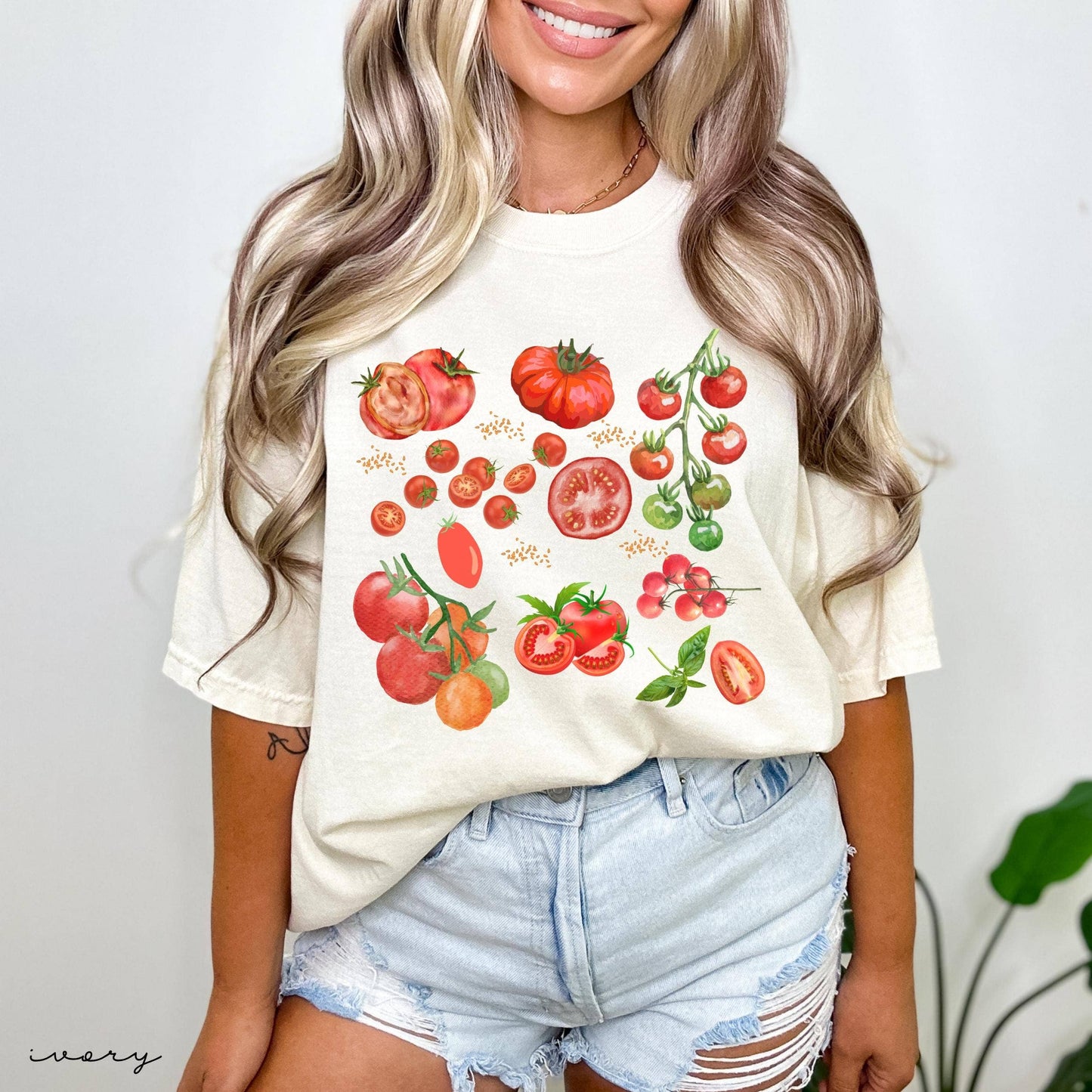 Woman wearing a white t-shirt with tomato graphics on a plain background