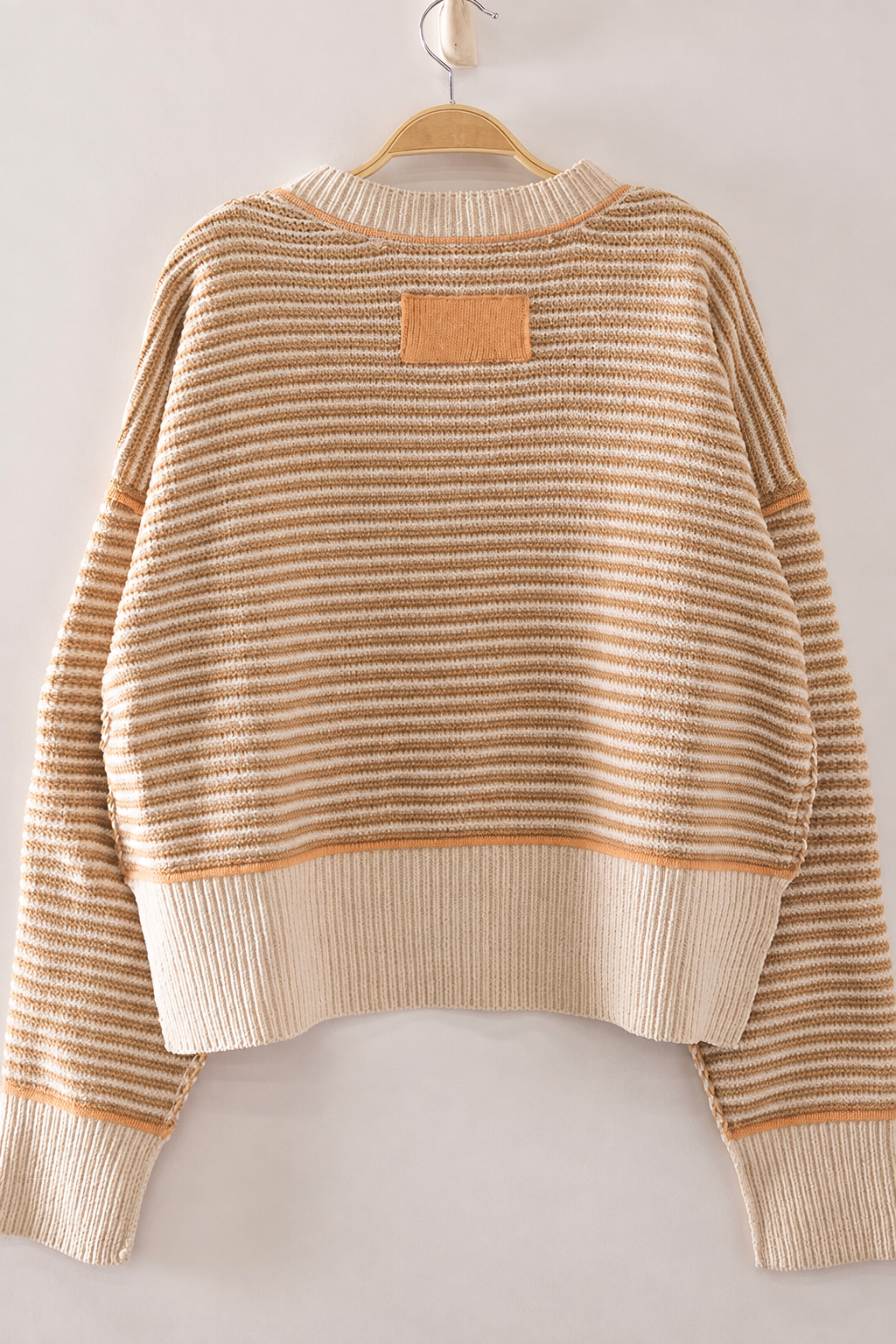 Back view of The Good Company Stripe Sweater in Toasted Oat featuring neutral stripes, a wide ribbed hem, and a small apricot knit patch.
