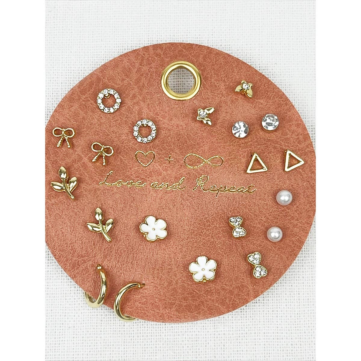 Round pink jewelry tray with various earrings on a white background