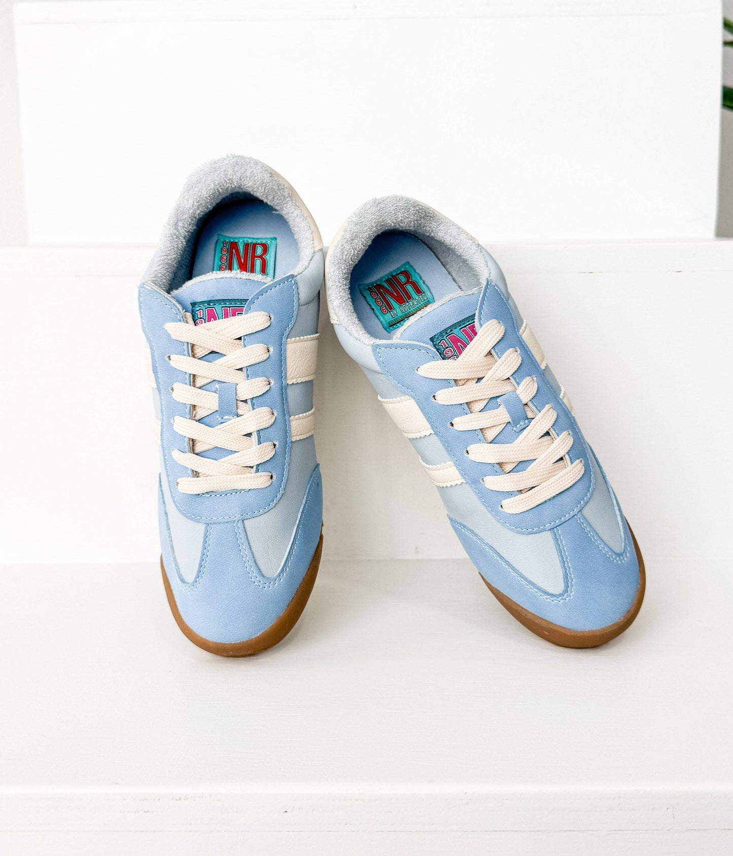 Overhead view of soft blue vintage sneakers with cream stripes and cozy sherpa interior.