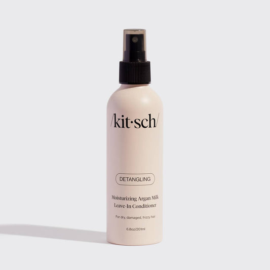 Kitsch Moisturizing Argan Milk Leave-In Conditioner bottle with black spray top on neutral background.
