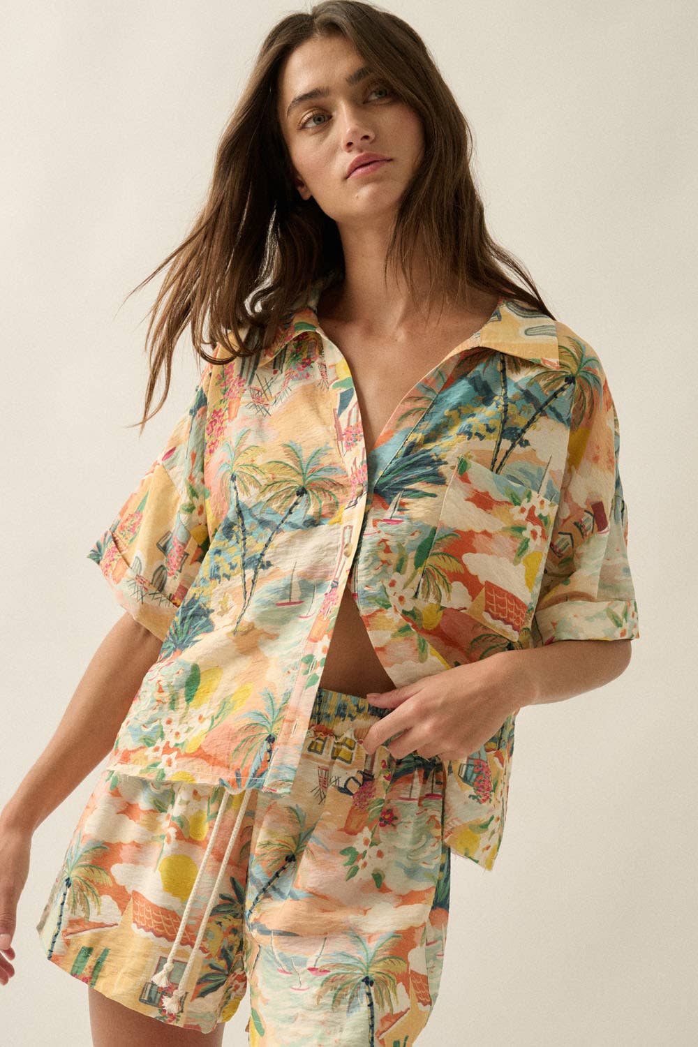 Woman wearing a colorful tropical print shirt and pants on a plain background