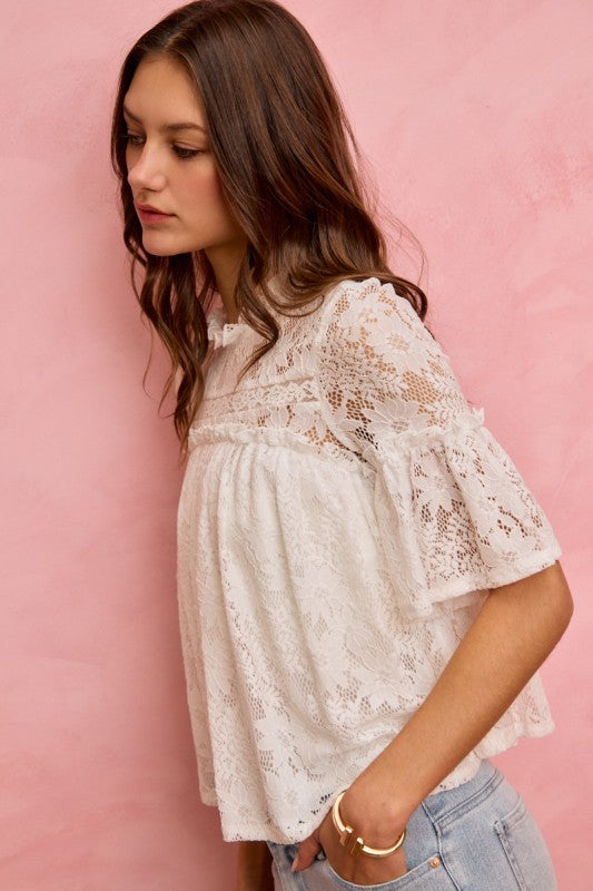 Woman wearing a white lace blouse against a pink background