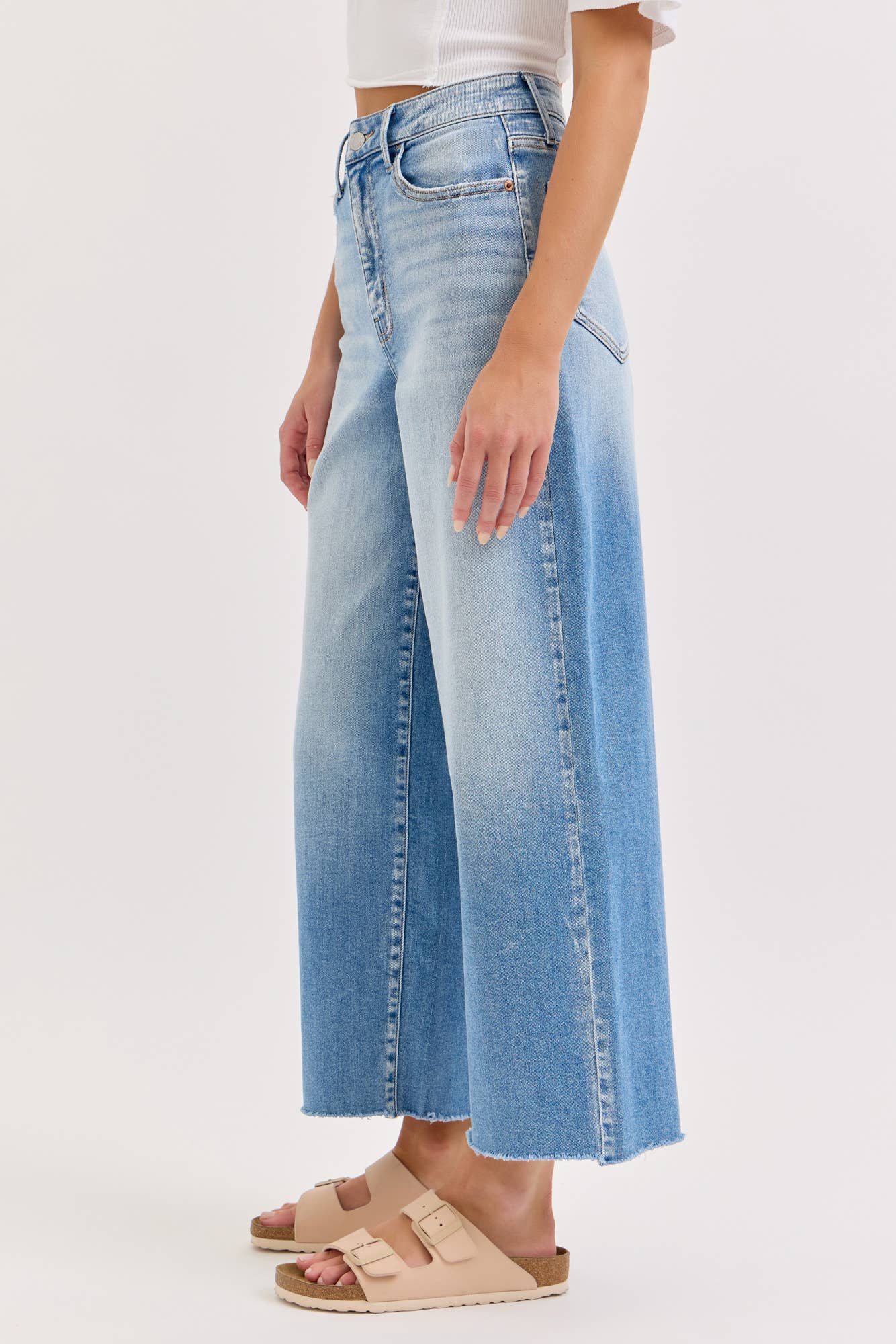 Person wearing light blue wide-leg jeans on a white background