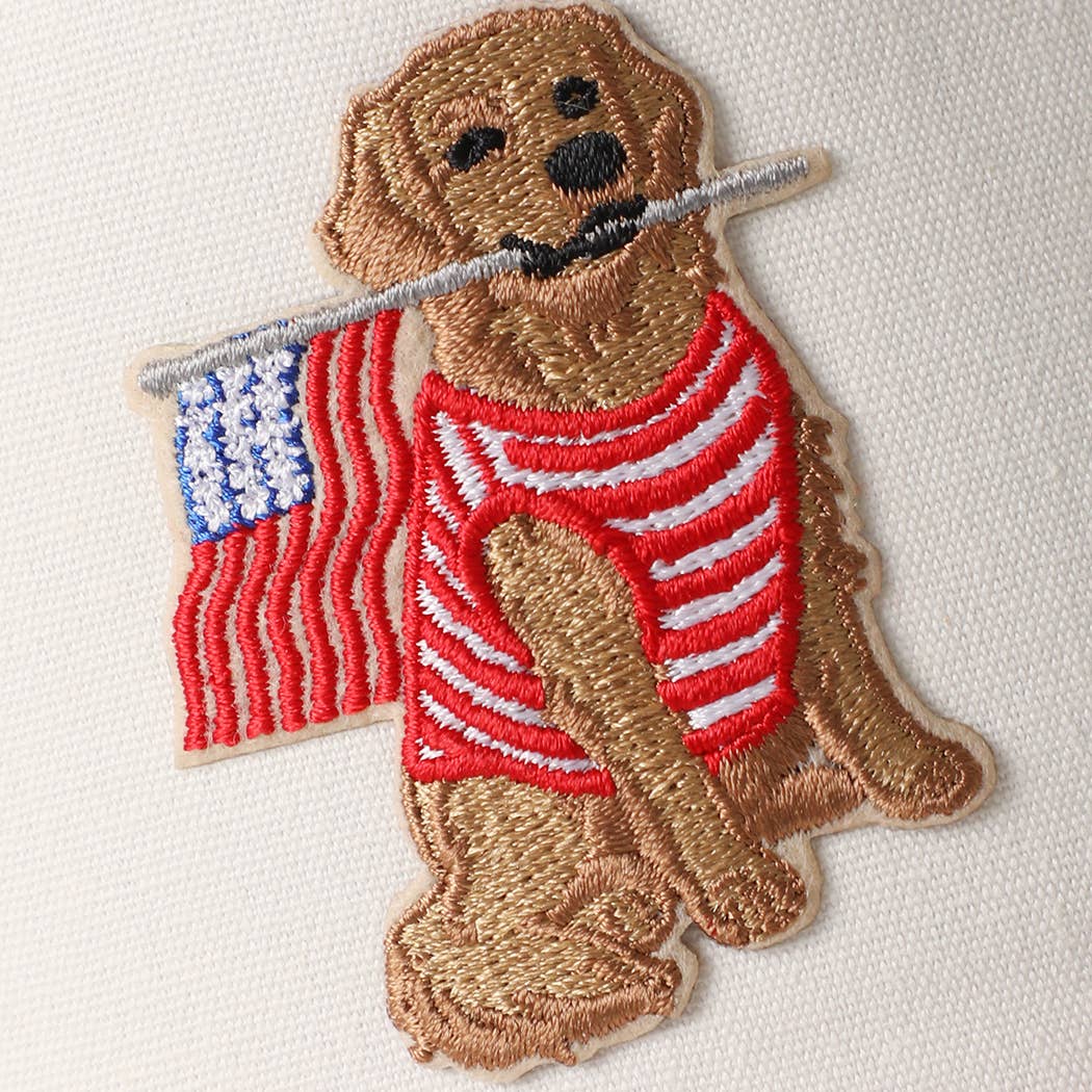 Embroidered patch of a dog holding an American flag on a white background