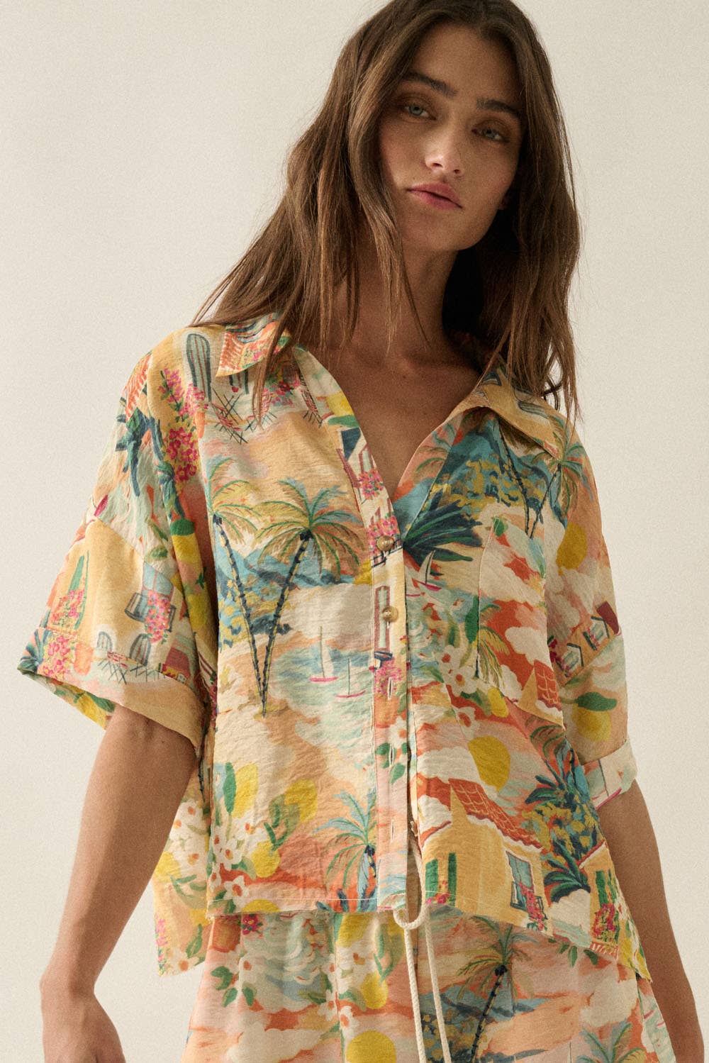 Woman wearing a colorful tropical patterned shirt against a plain background