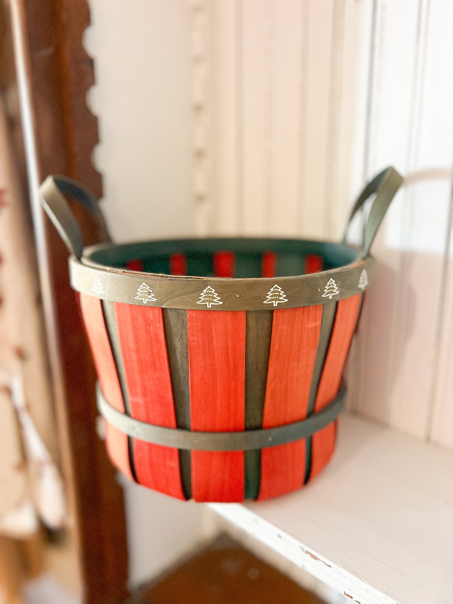 Vintage red and green wooden Christmas basket with tiny white tree accents along the rim.