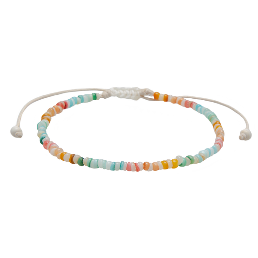 Handcrafted puka shell anklet featuring genuine shell beads, colorful accent beads, and an adjustable cotton cord inspired by coastal summer style.