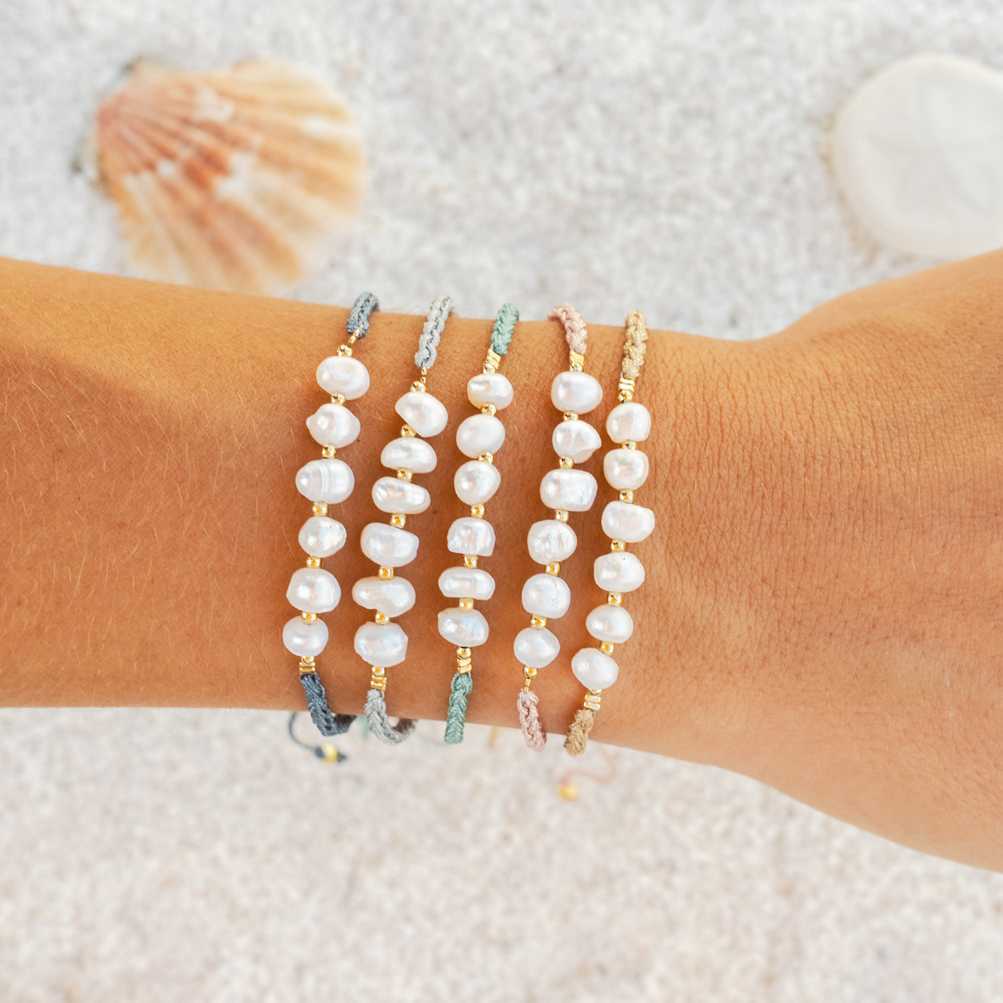 Pearl bracelets on a wrist with a beach background