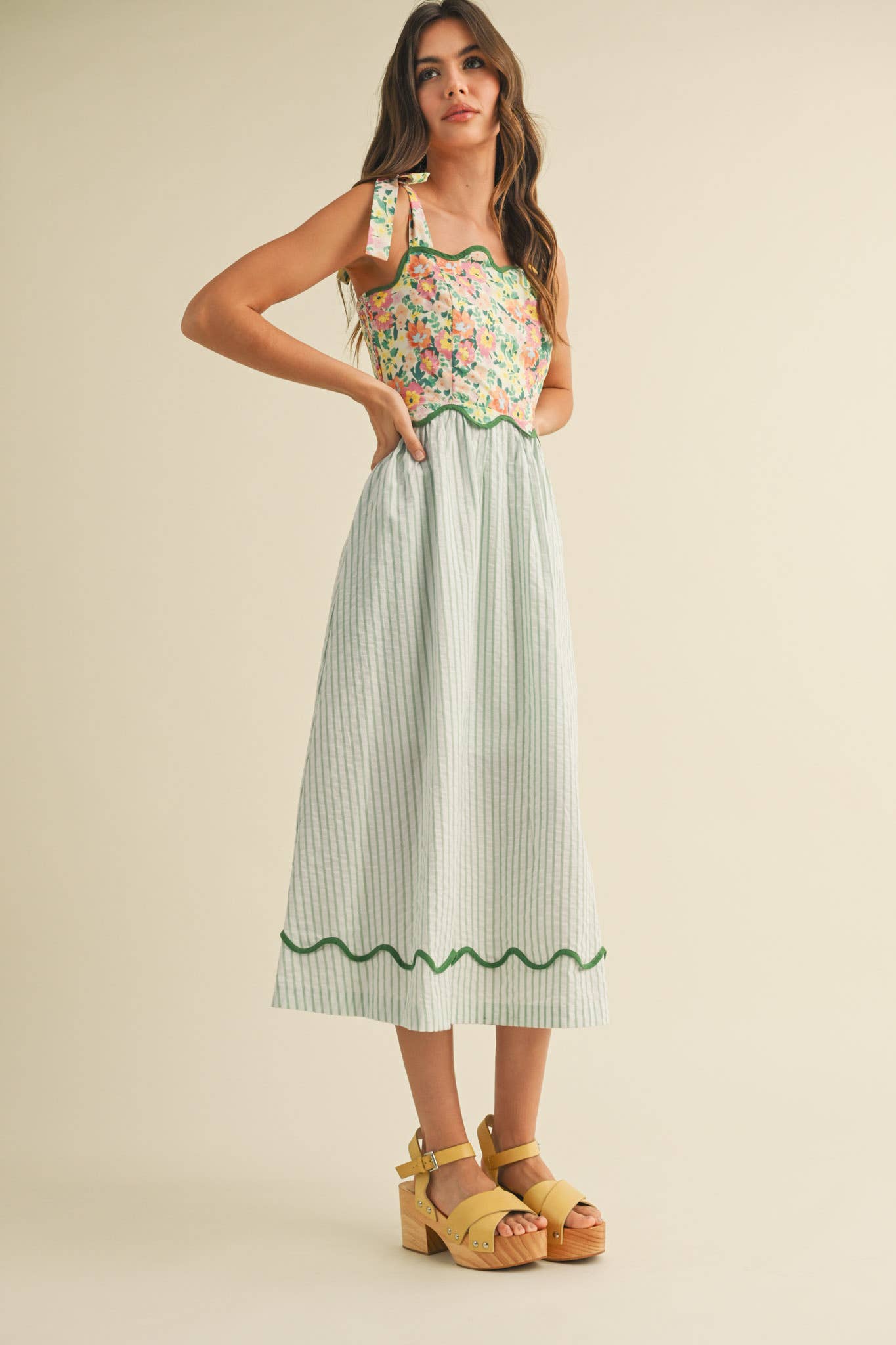 Woman wearing a floral top and striped skirt on a beige background