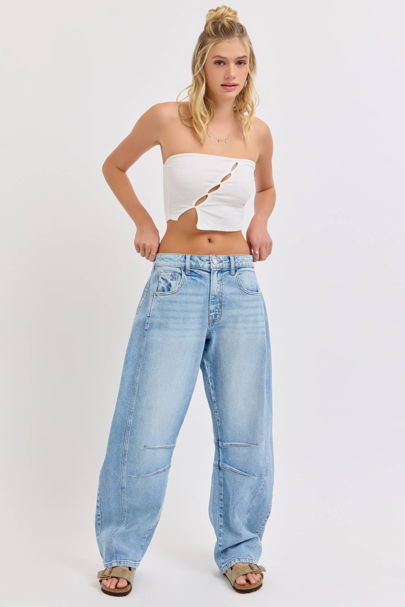 Woman wearing a white strapless top and light blue jeans on a white background