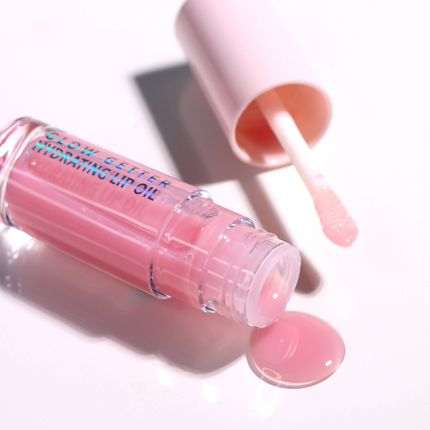 Pink lip balm with applicator on a white background