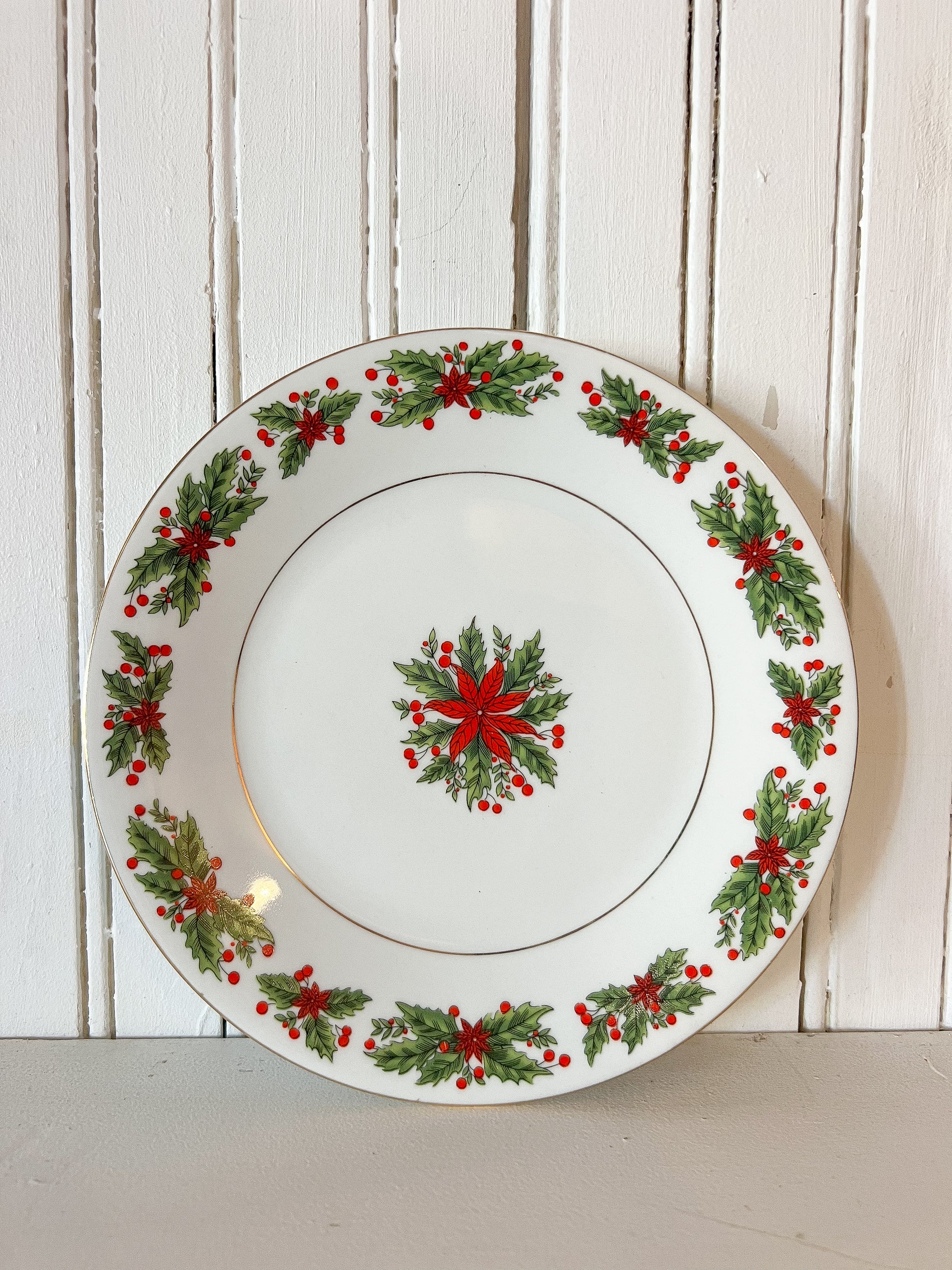 vintage white porcelain Christmas plate with red poinsettias and green holly leaf pattern around the edge