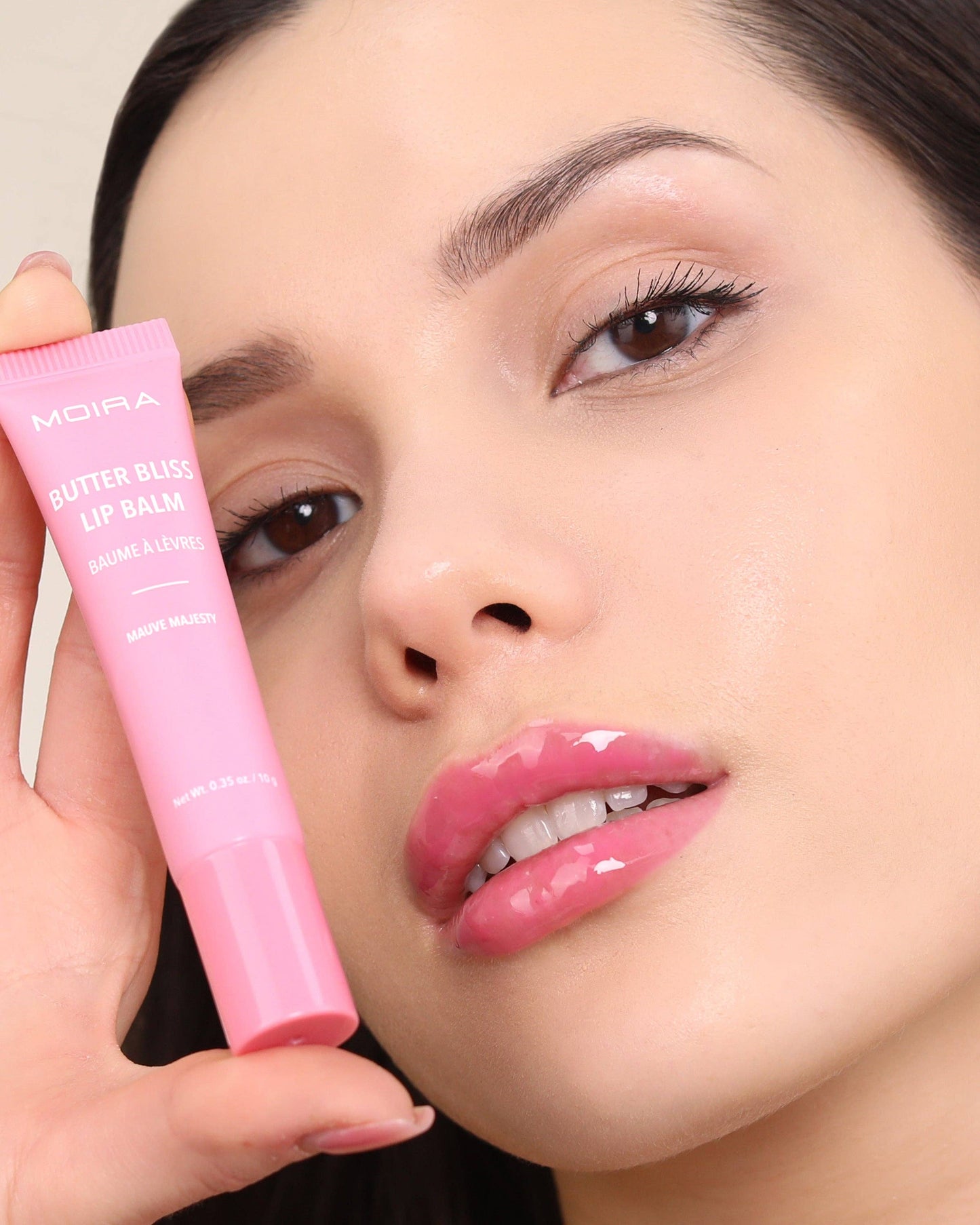 Woman holding a pink lip balm with 'MOIRA' branding