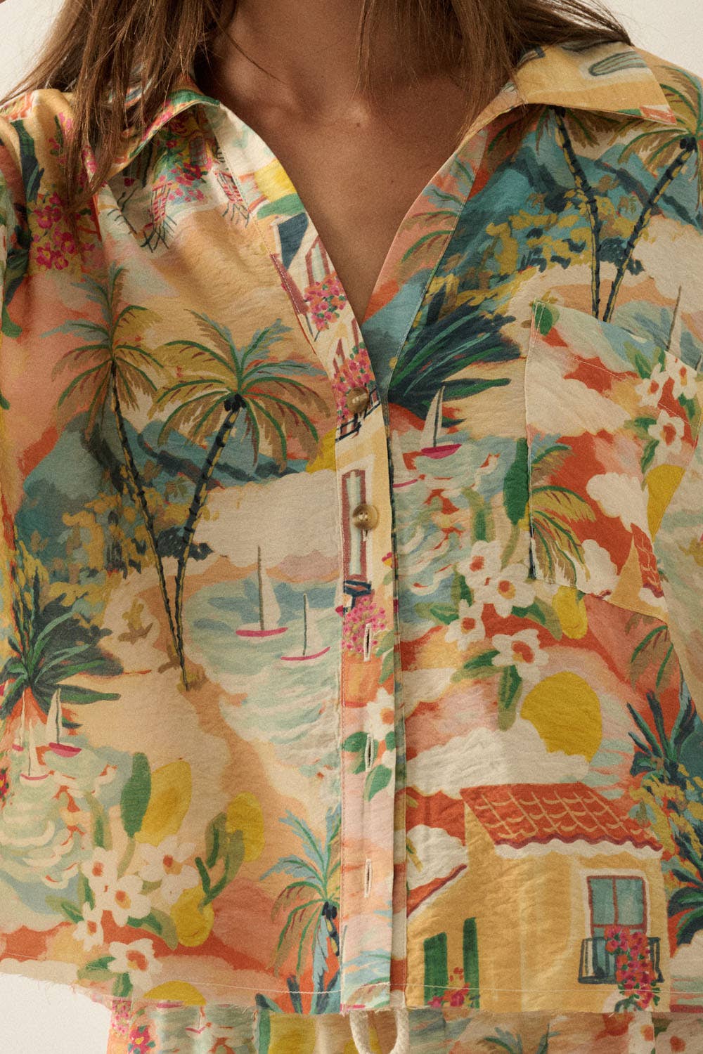 Close-up of a colorful tropical patterned shirt with palm trees and houses.