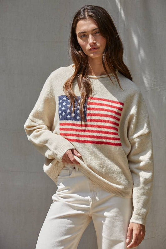 Cream knit sweater featuring a large American flag jacquard design on the front with a relaxed fit and long sleeves.