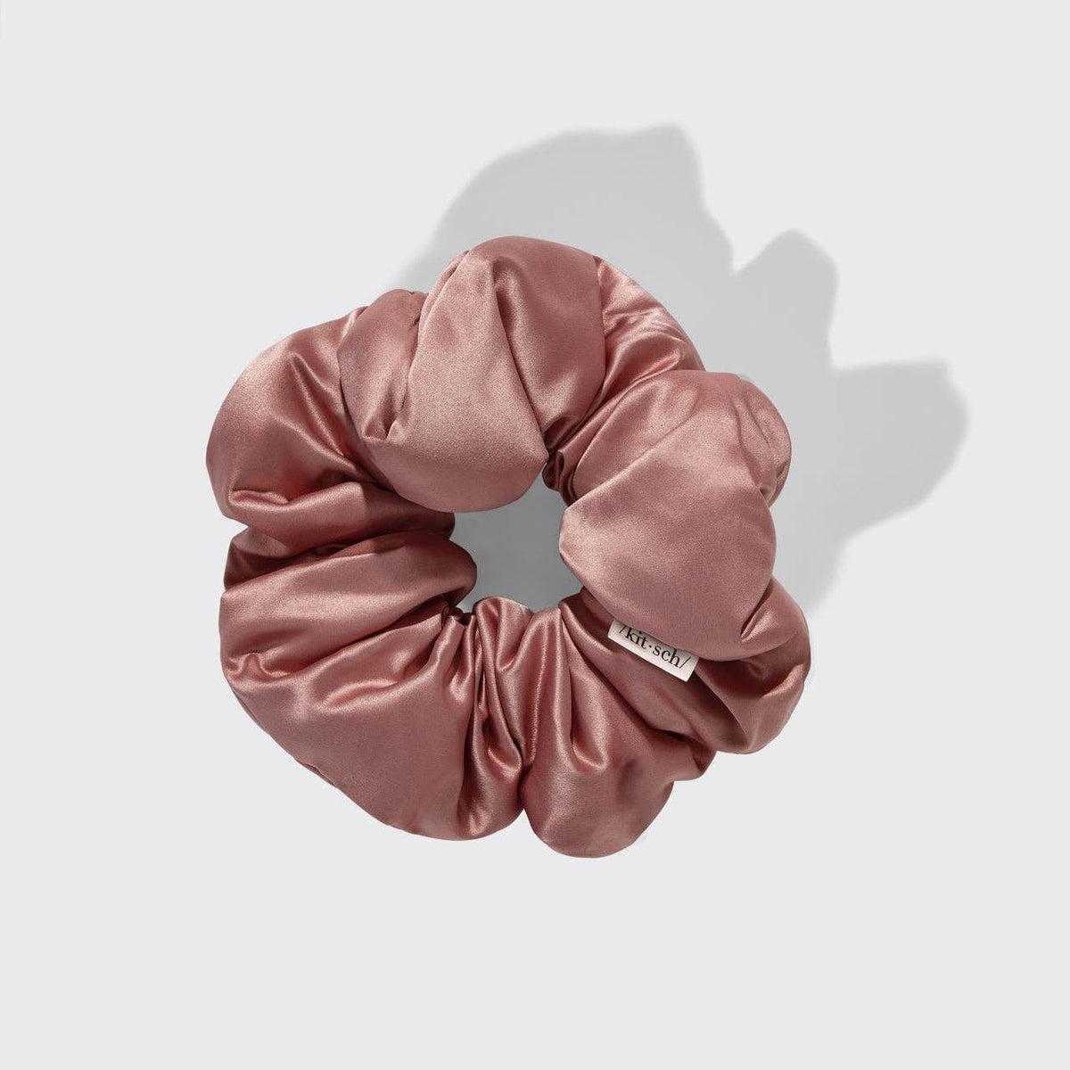 Pink satin scrunchie on a light gray background