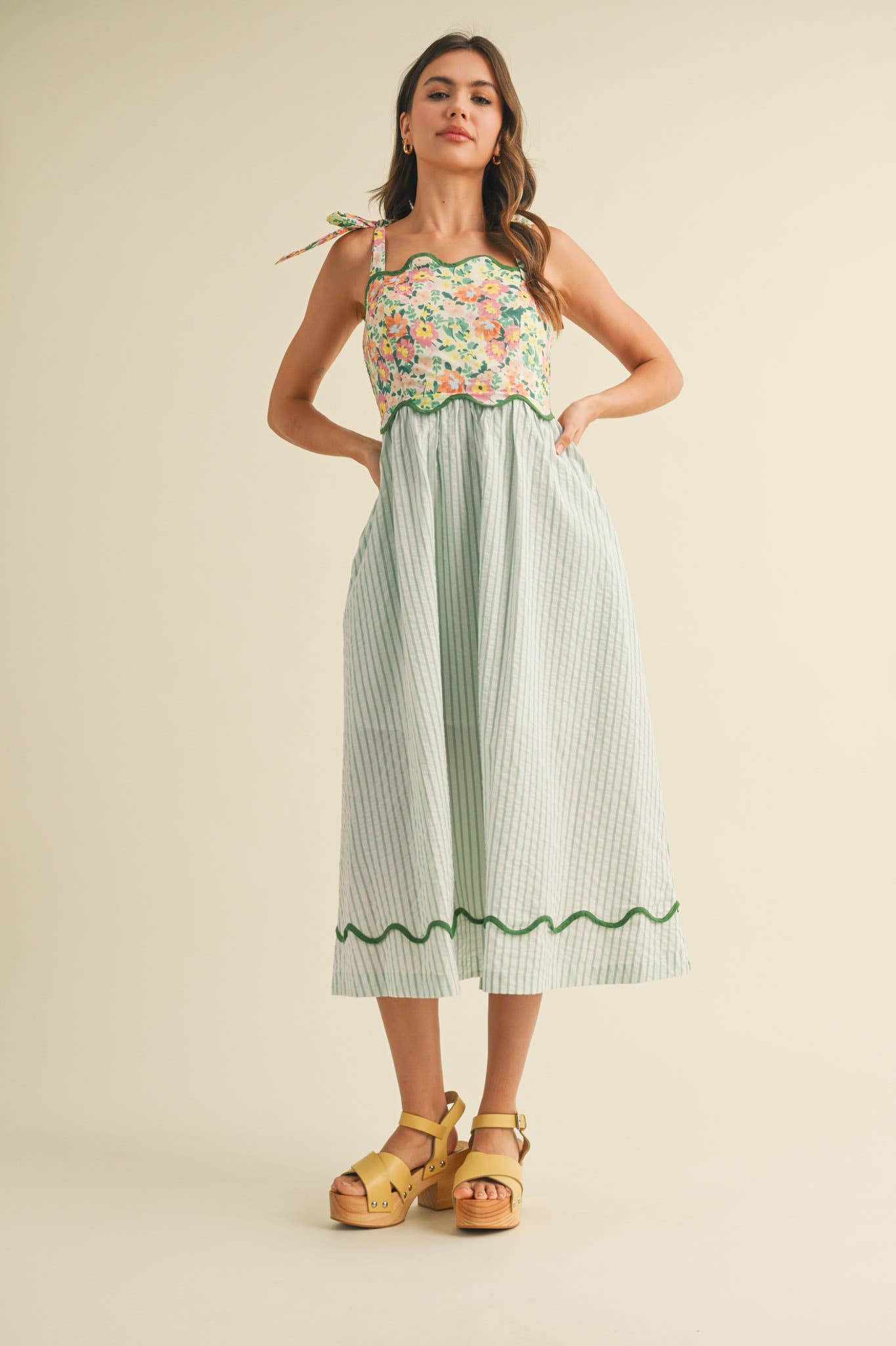 Woman wearing a floral top and green striped skirt on a beige background