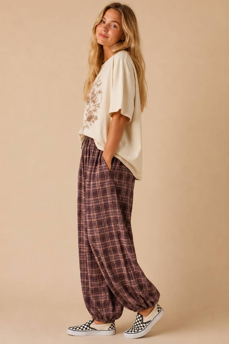 Woman wearing a white top and plaid pants on a beige background