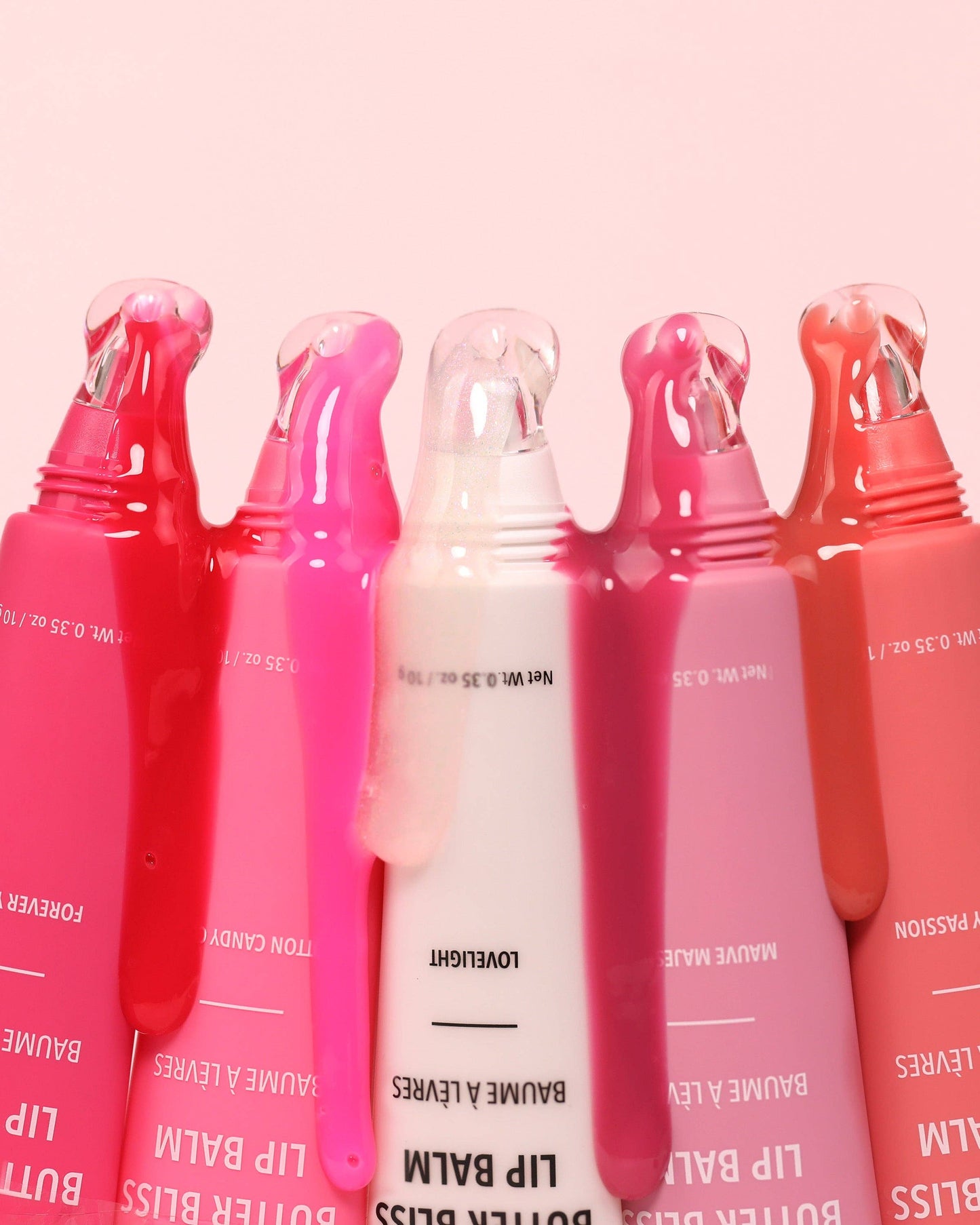 Set of lip balm tubes with visible branding on a pink background