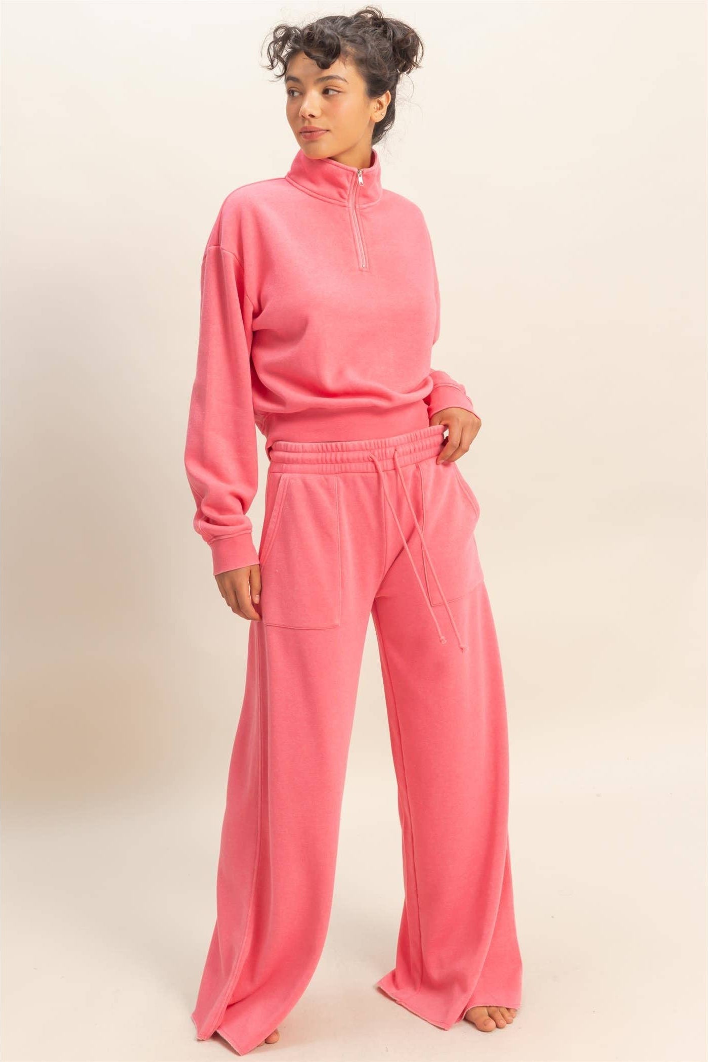 Woman wearing a pink tracksuit against a plain background