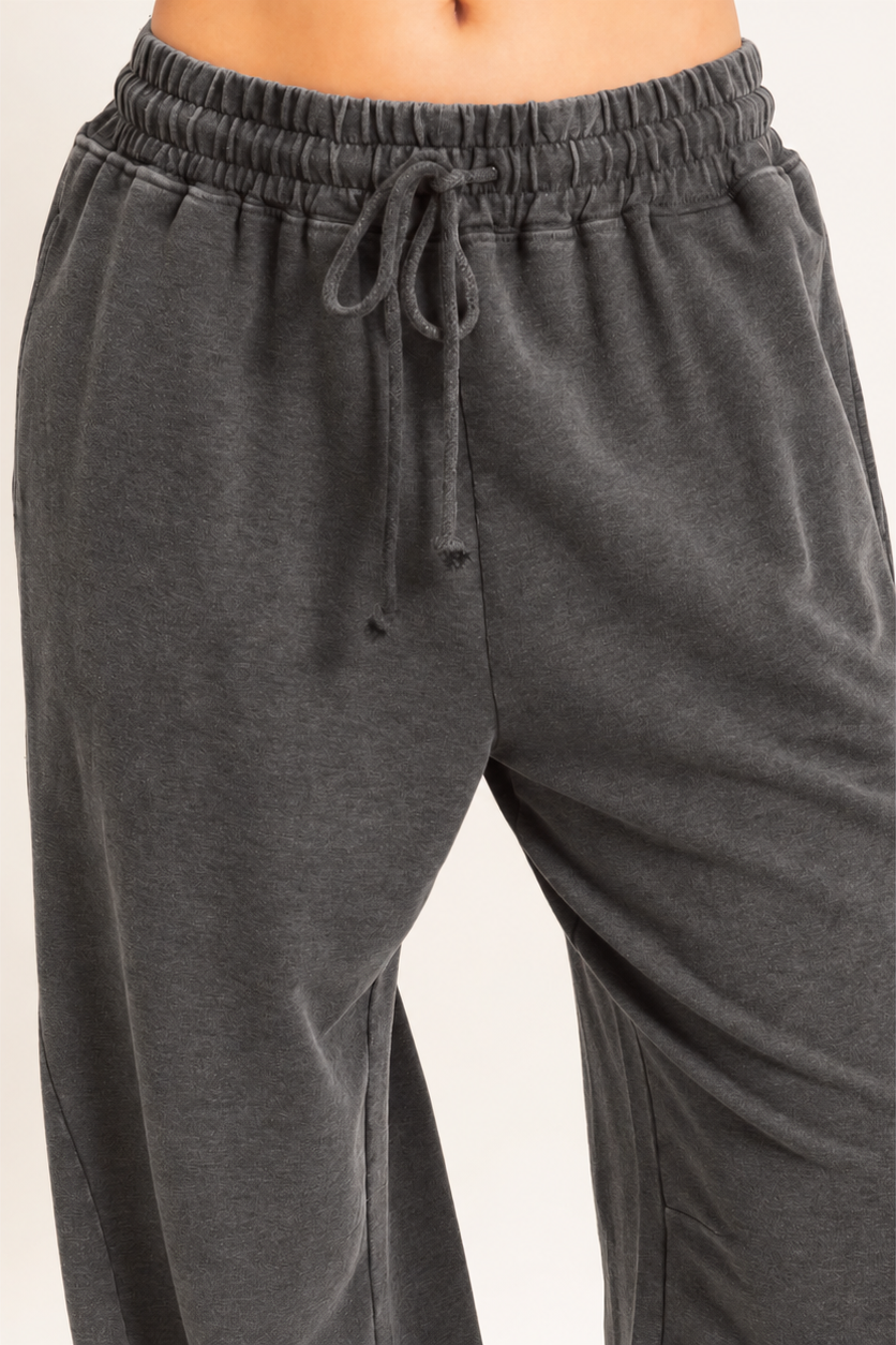 Dark gray heathered sweatpants with an elastic drawstring waistband, shown on a model cropped from the waist down against a plain light background.