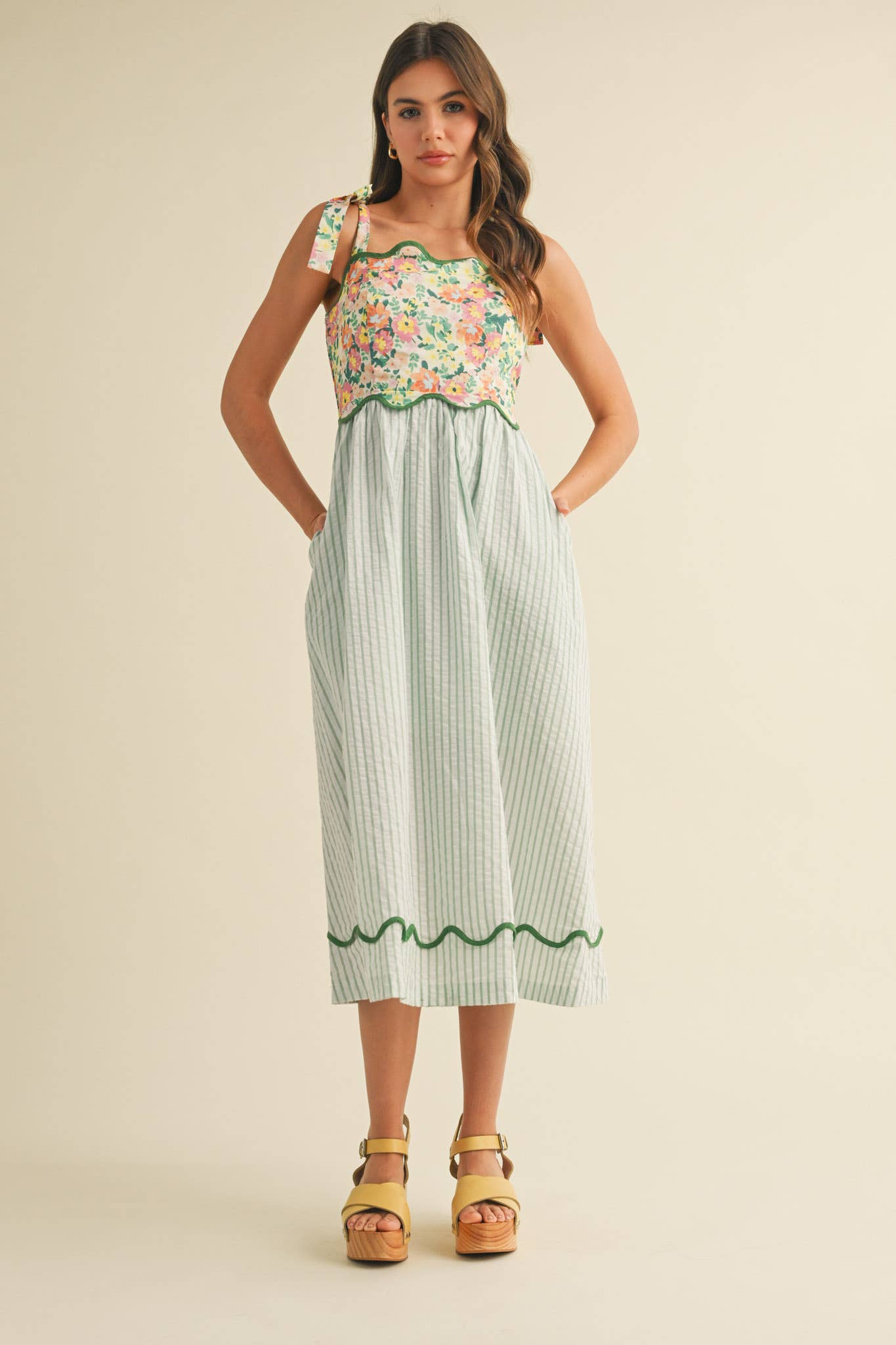 Woman wearing a floral top and striped skirt on a beige background