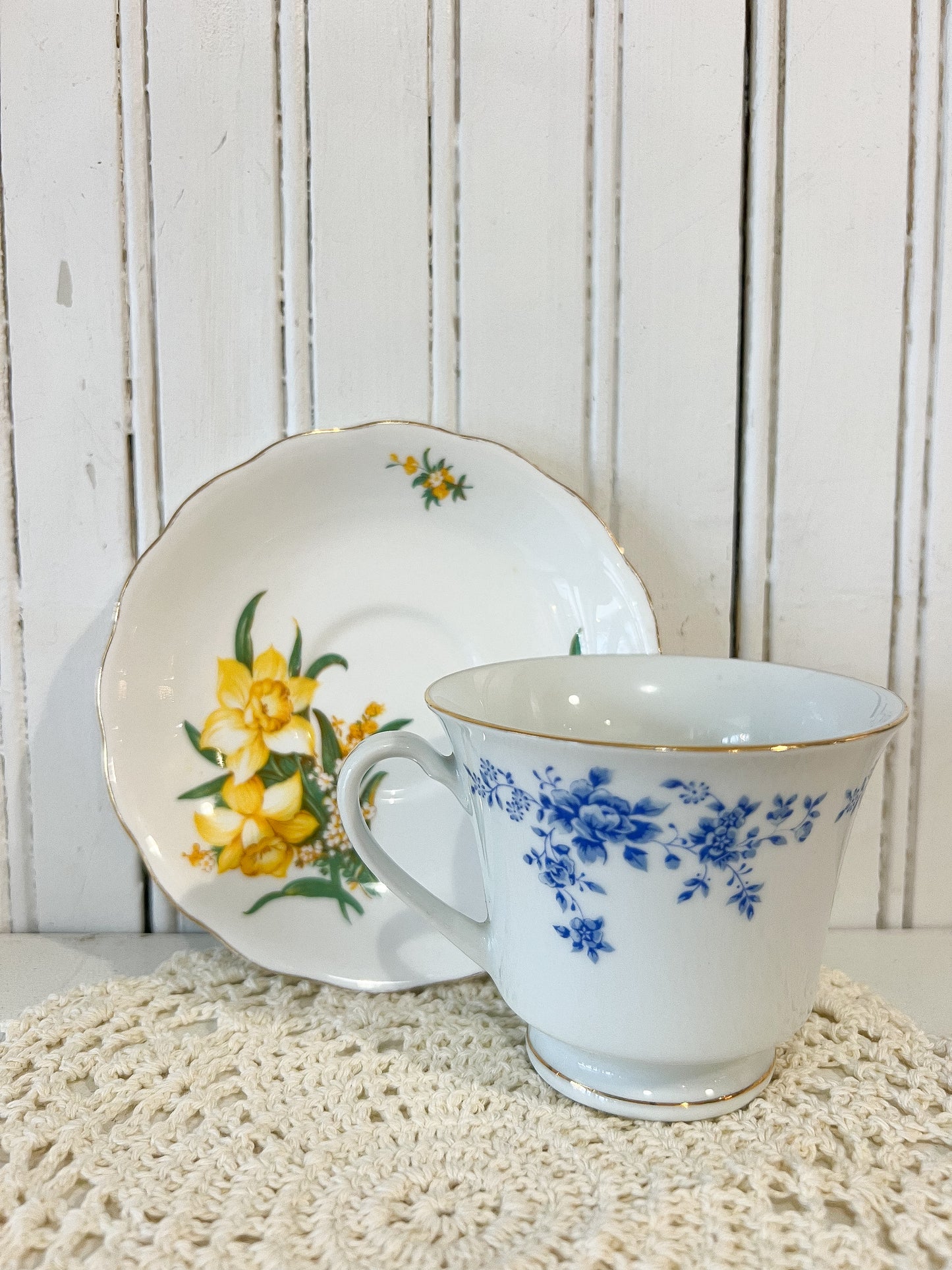Teacup and saucer with floral design on a textured surface and wooden background