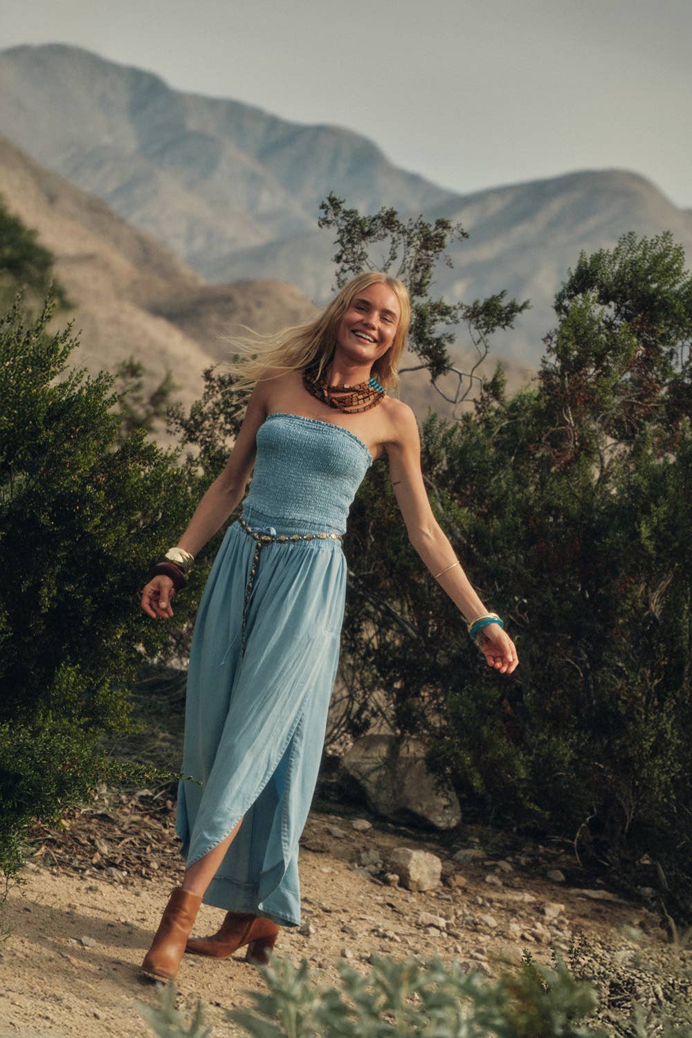 Woman in a blue dress standing in a mountainous landscape