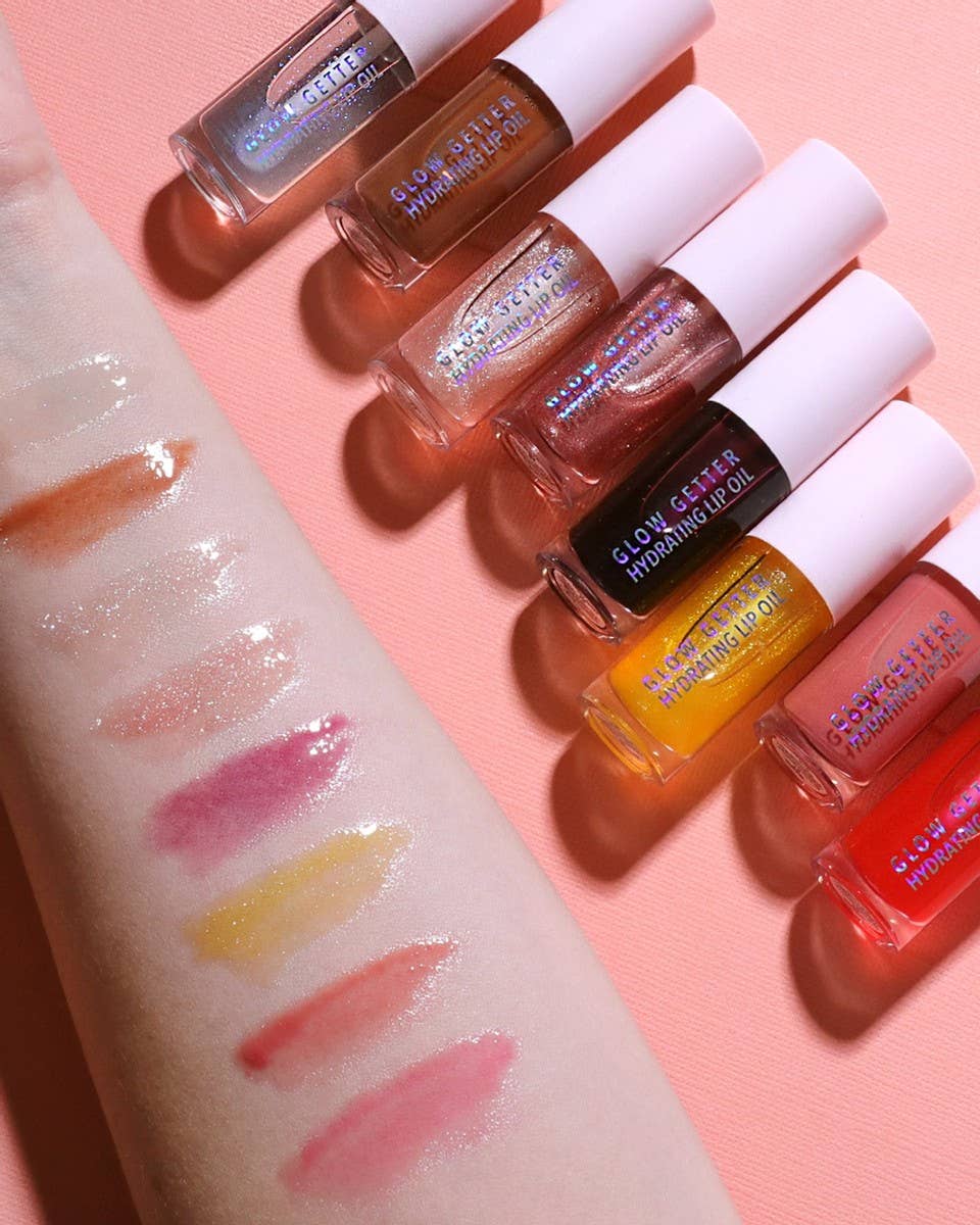 Set of lip glosses with swatches on a pink background