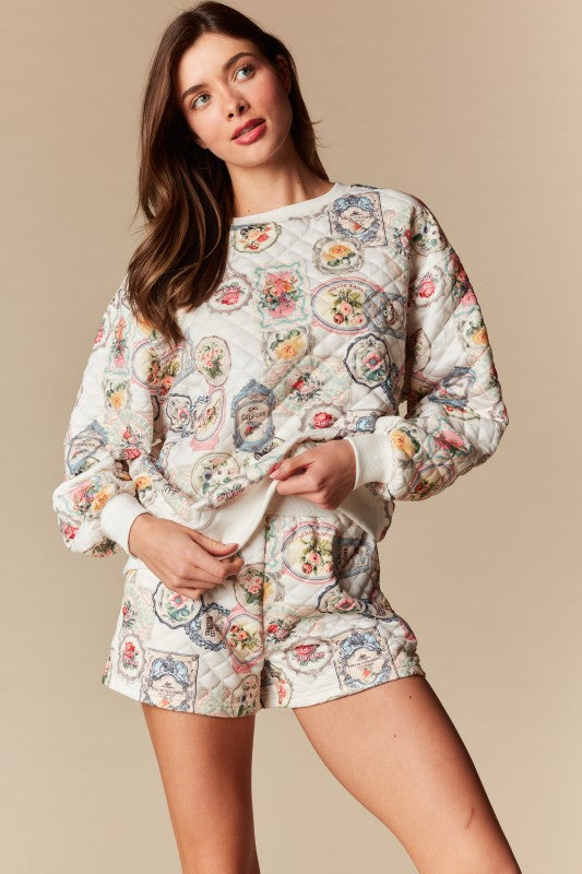 Woman wearing a vintage-inspired quilted floral lounge set featuring a patchwork label print and matching shorts.