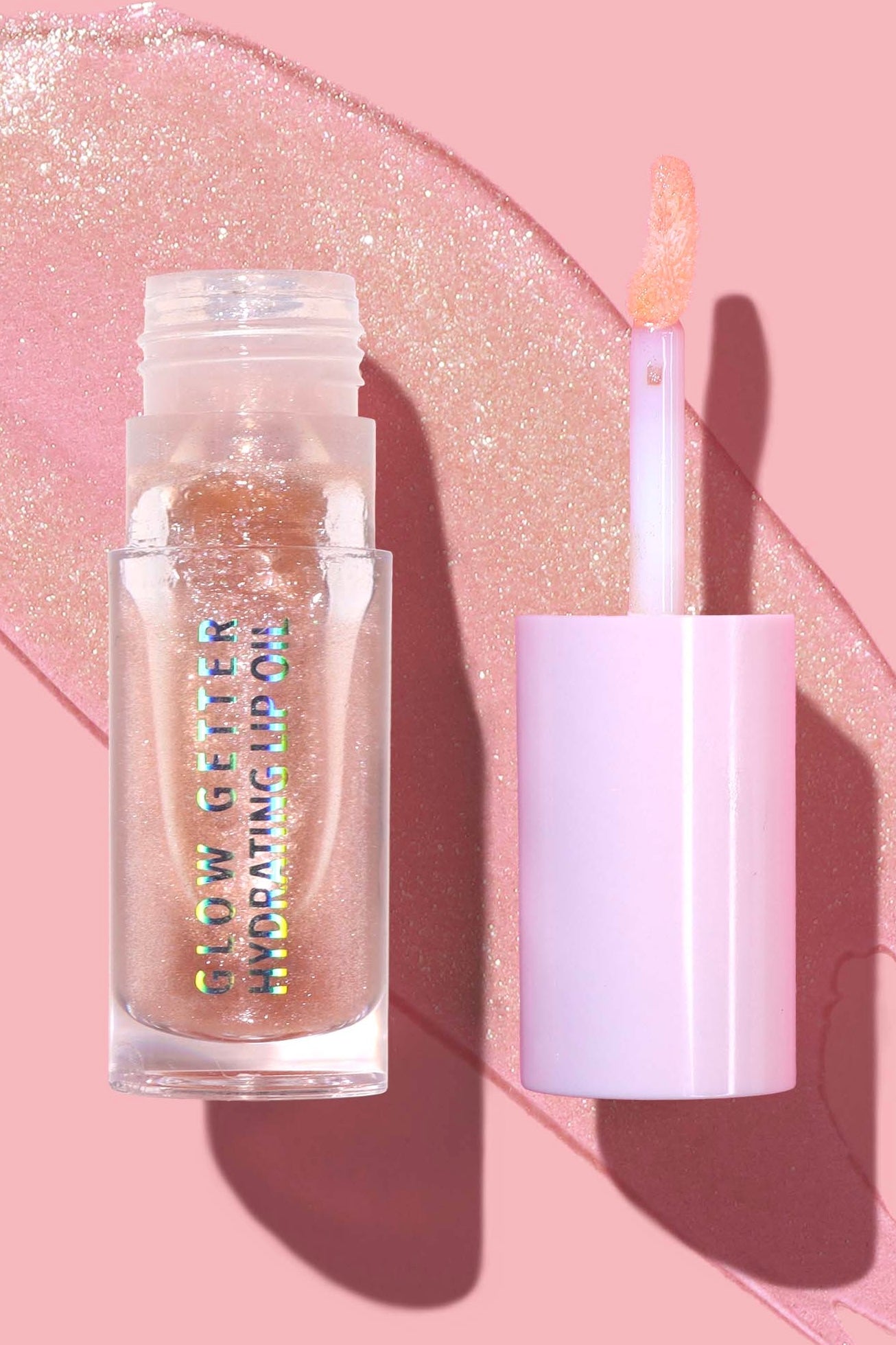 Lip gloss with applicator on a pink glittery background