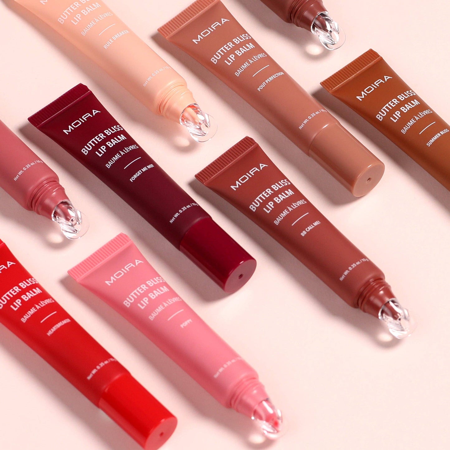 Moira Butter Blush Lip Balms in various shades on a light pink background
