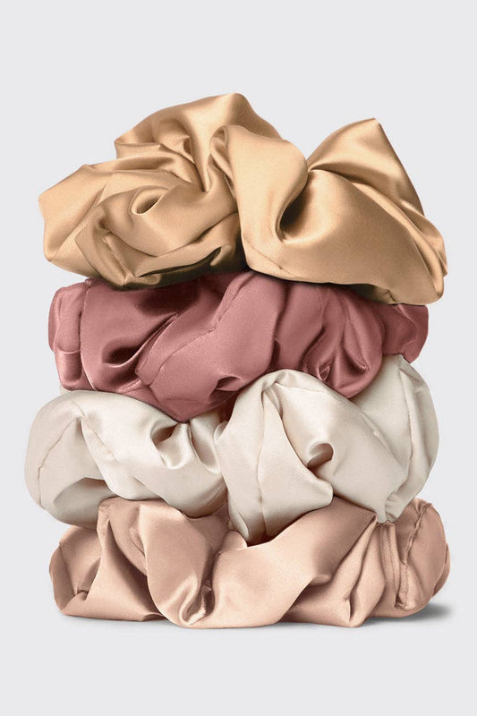 Stack of beige, pink, and white satin pillow scrunchies on a light gray background