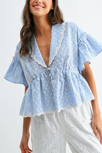 Woman wearing a blue checkered blouse with ruffled details on a white background