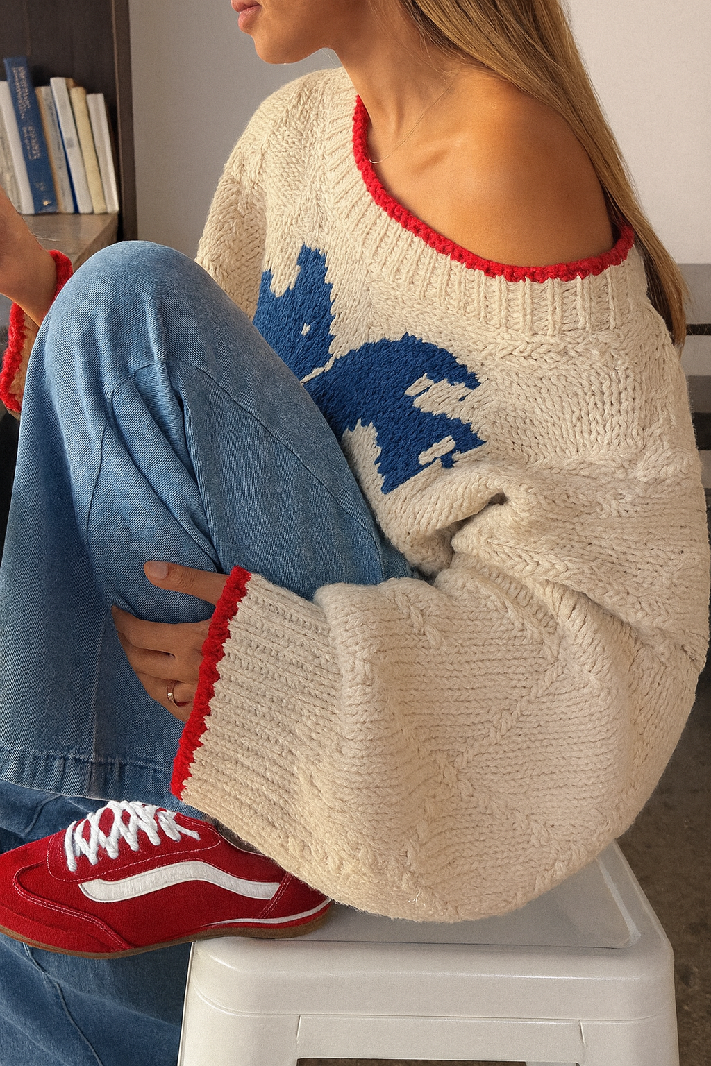 Close-up view of a woman wearing the Campus Catch Knit with wide cuff denim and red sneakers, showing the off-the-shoulder neckline and relaxed, cozy fit.