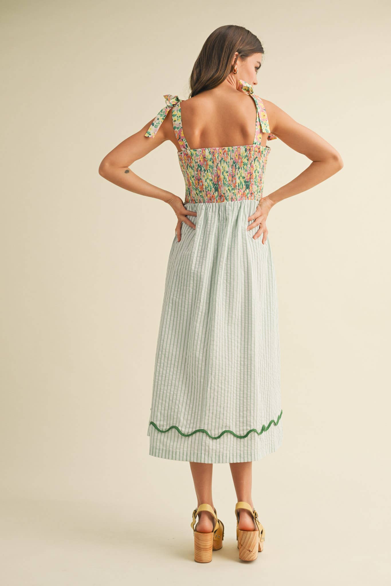 Woman wearing a floral top and green striped skirt on a beige background