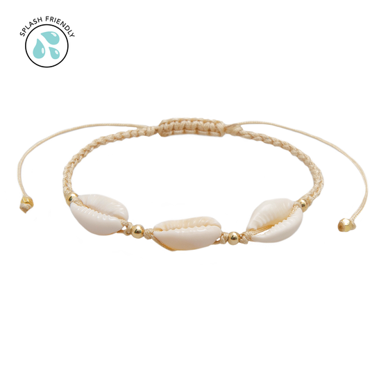 Handcrafted shell bracelet featuring natural white shells, gold accent beads, and an adjustable braided cord in a neutral sand color.