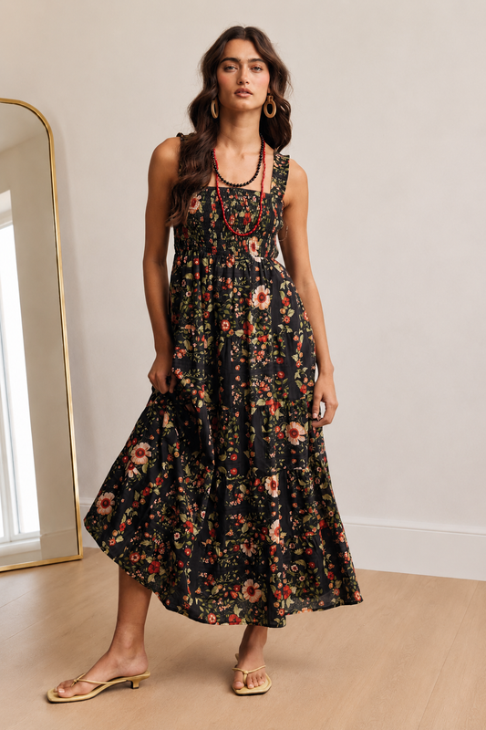 Front view of The Folk Tale black floral cotton maxi dress with a smocked bodice and tiered skirt
