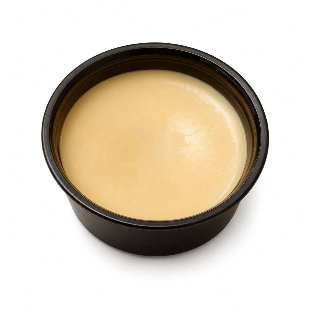 A round black plastic container filled with a smooth, pale beige cream or gel, shown from a top-down view on a white background.