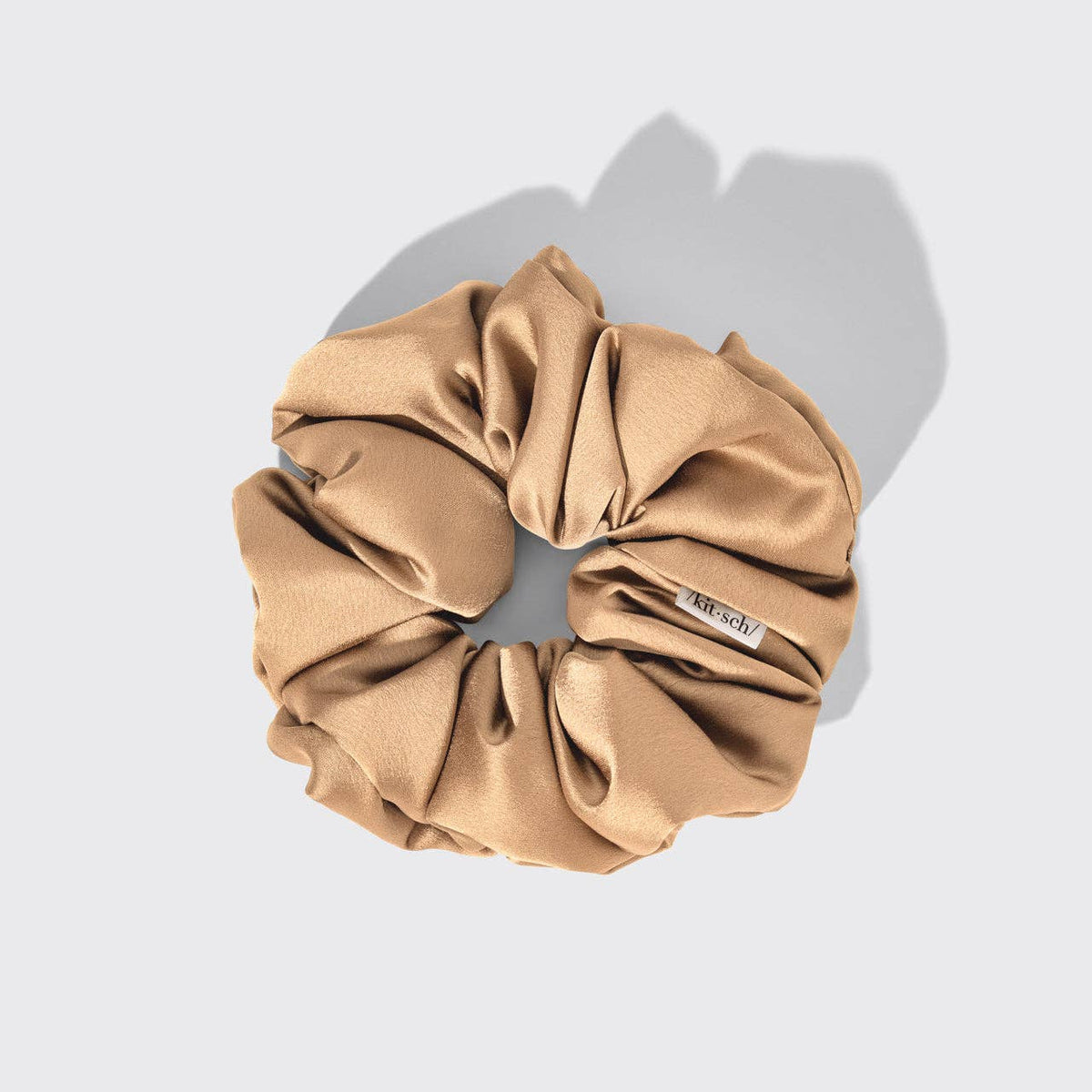 Beige scrunchie with brand label on a light gray background