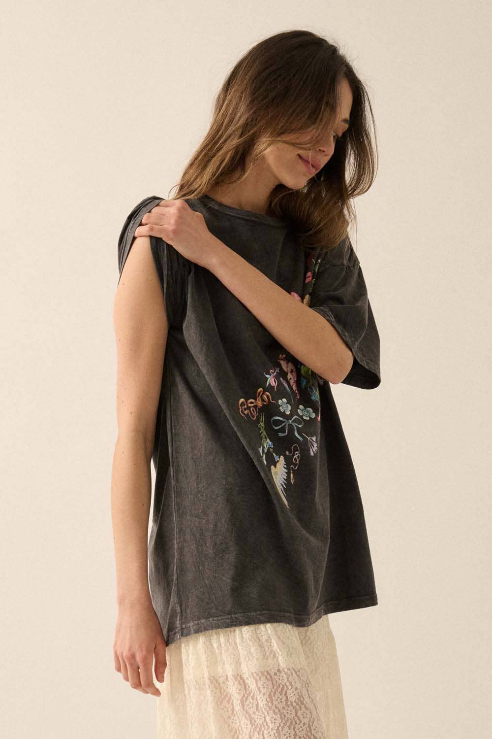 Woman wearing a dark gray t-shirt with floral embroidery on a beige background