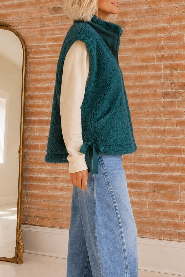     Side view of the Deep Spruce sherpa vest showing its relaxed boxy fit, front pocket, and adjustable tie side.