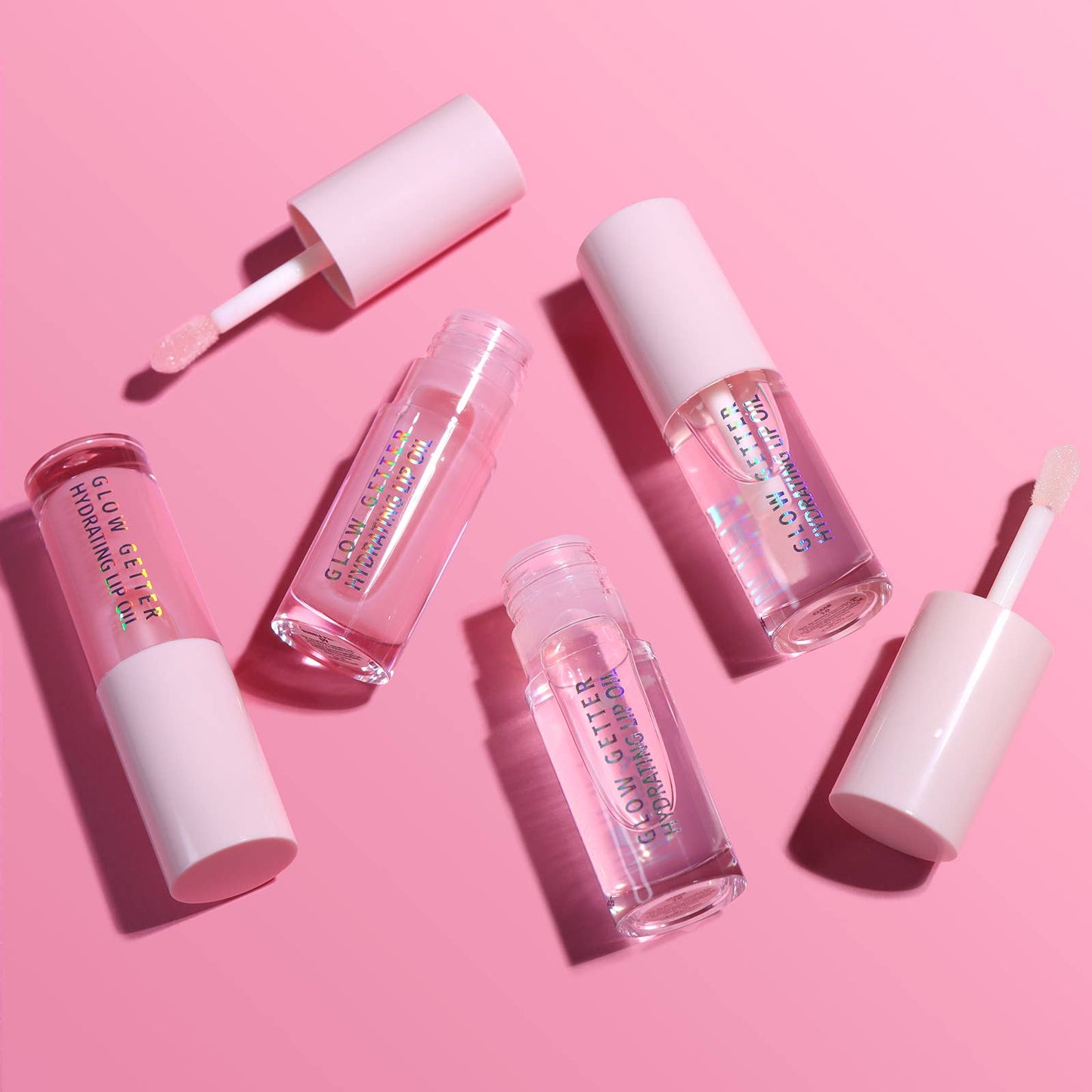 Set of lip gloss products on a pink background