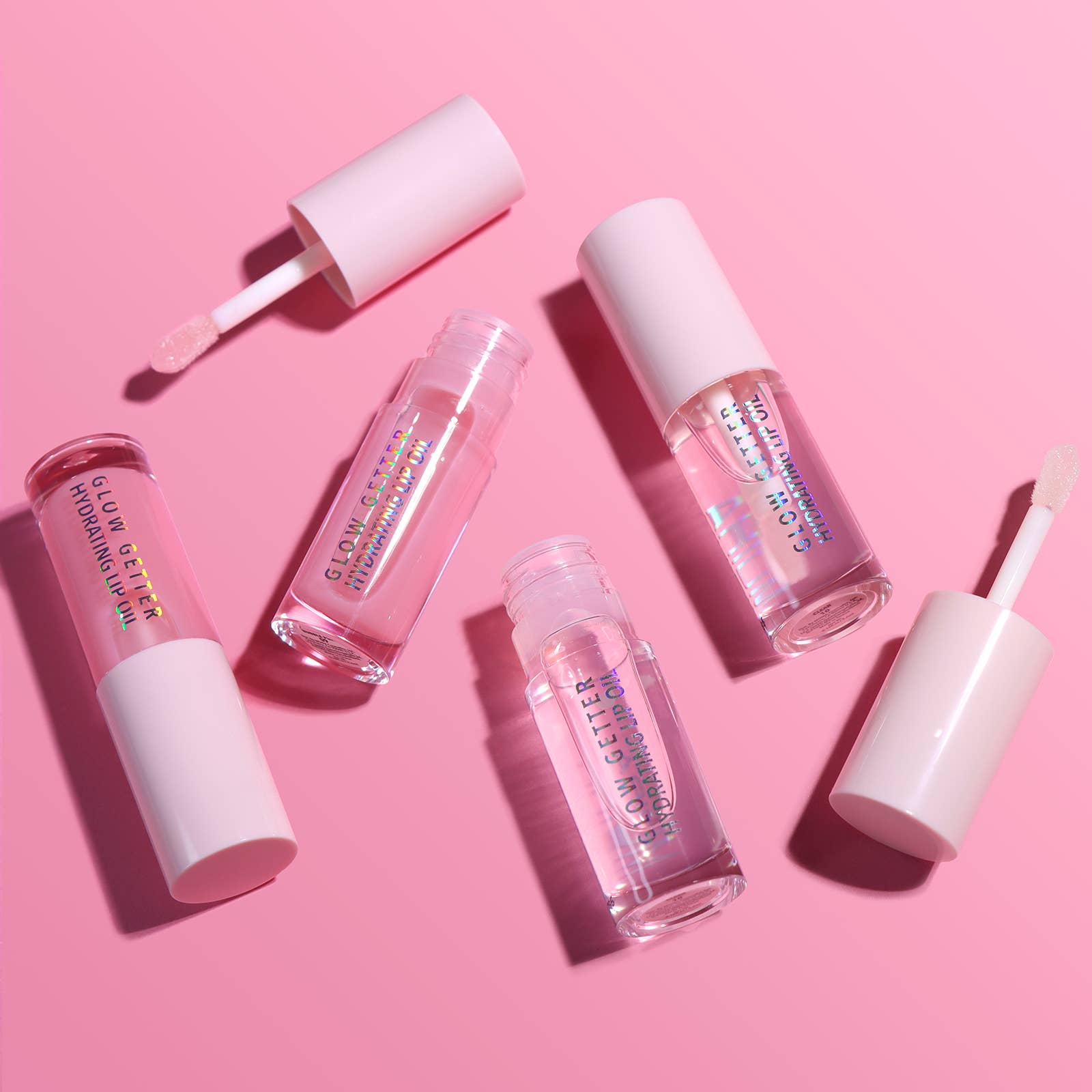 Set of lip gloss products on a pink background